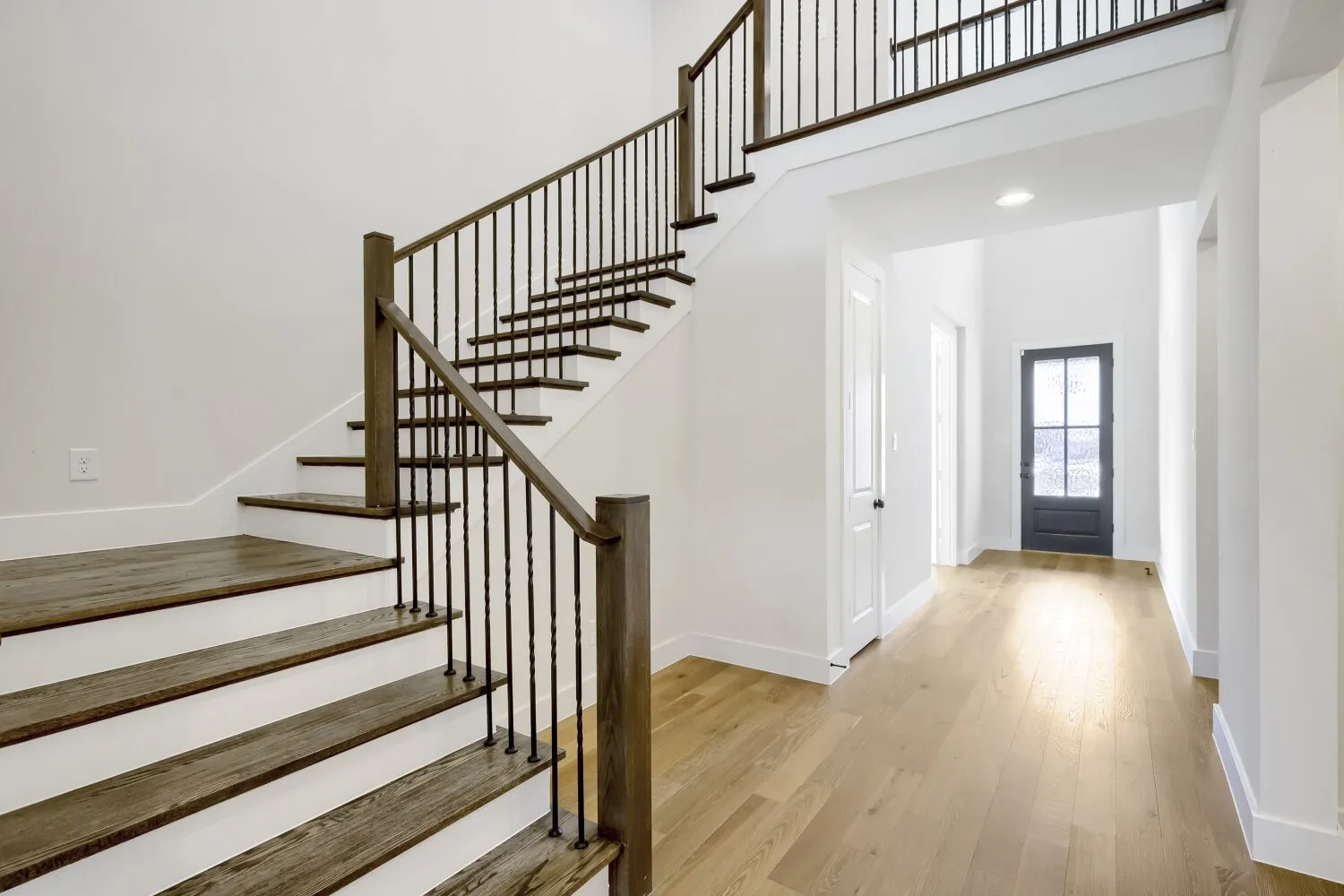 Grand entry featuring a two-story staircase with wood-finish treads and wrought iron balusters