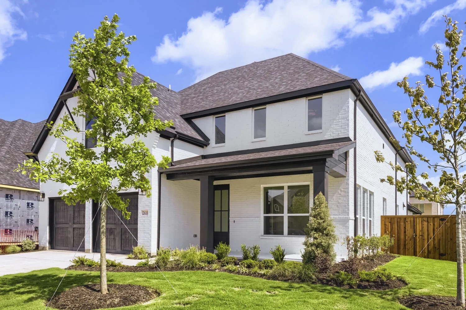 Two-story residence featuring white brick exterior and a dark shingle roof