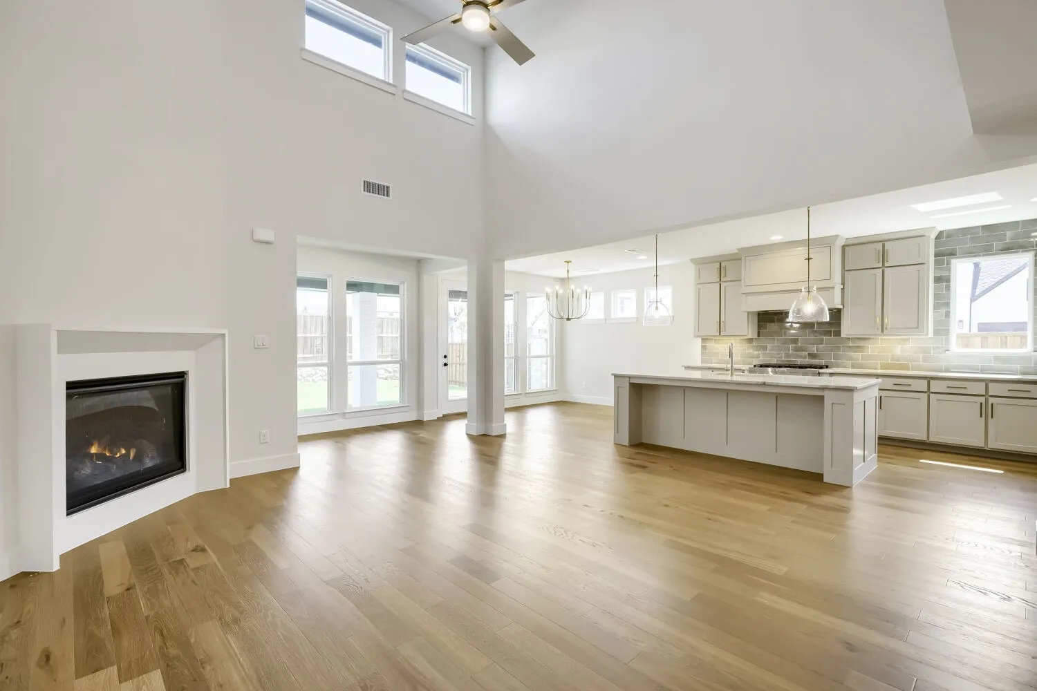 Open-concept living space featuring wood-finish flooring, a contemporary fireplace, and a high vaulted ceiling