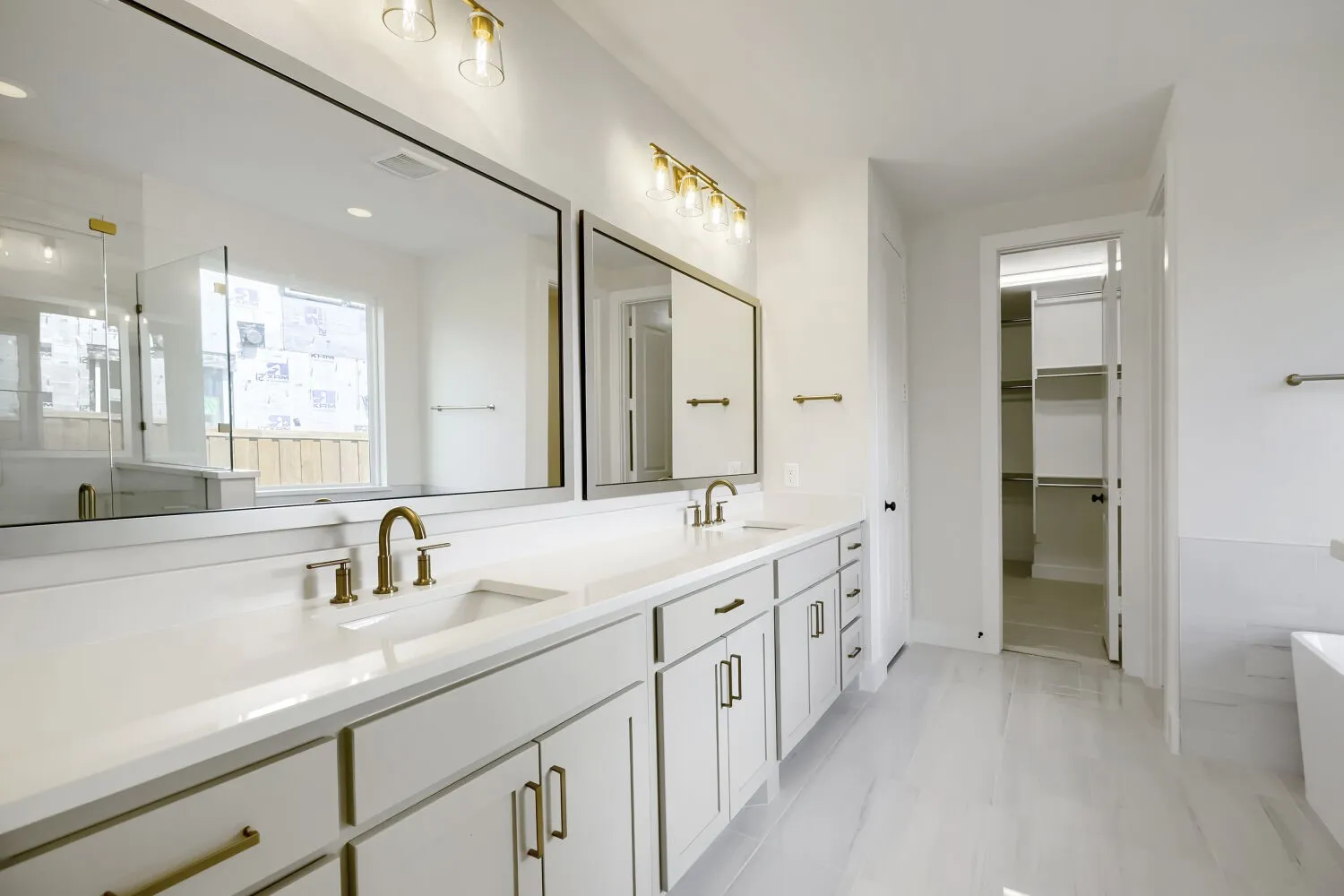 Spacious bathroom featuring an extended double vanity with undermount sinks and brass-finish fixtures