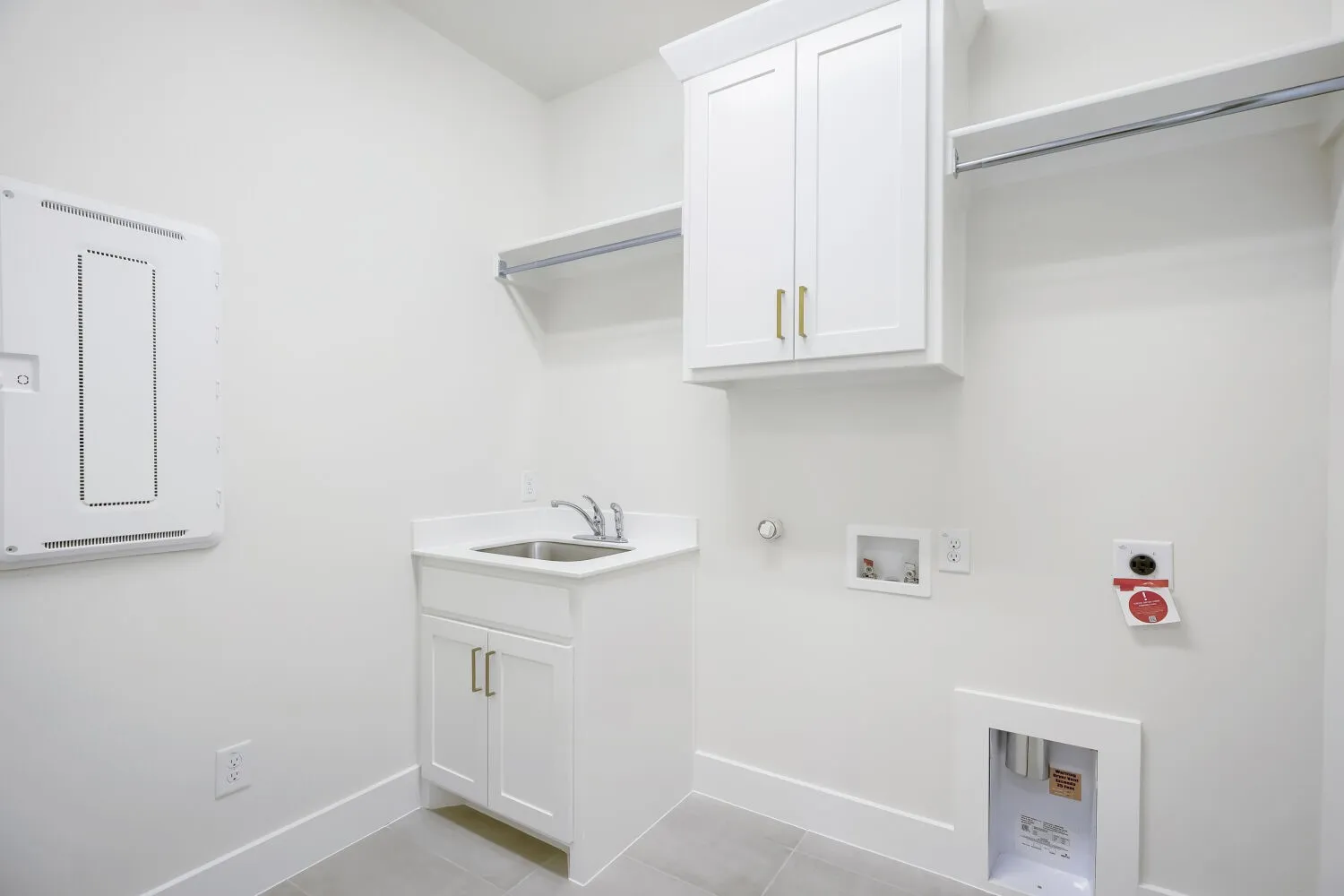 Utility room featuring a built-in sink with a countertop, white cabinetry with gold-tone hardware, and a built-in hanging rod with shelving