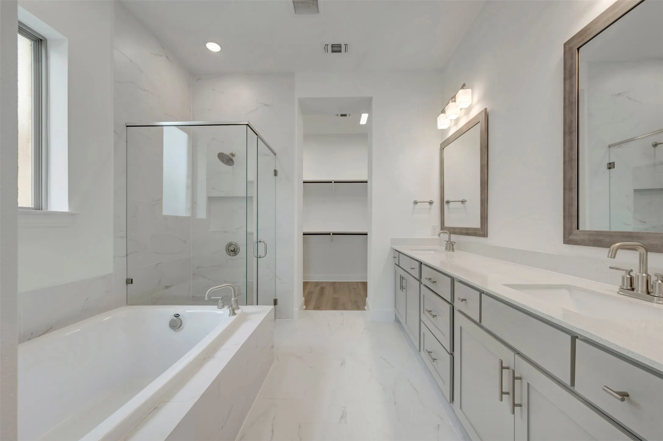Dual vanity with quartz countertops, a glass-enclosed shower, a built-in soaking tub, and tile flooring