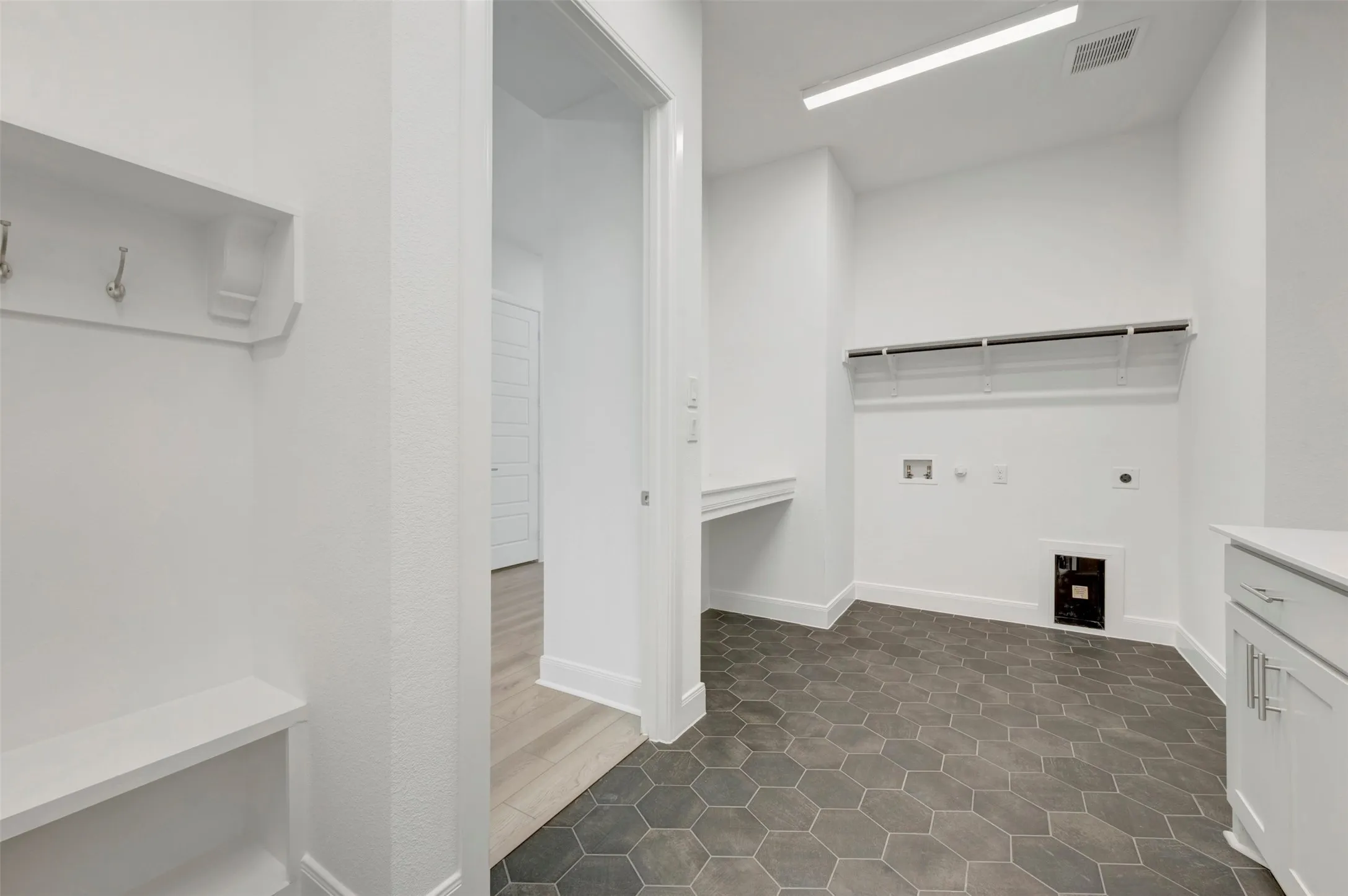 Hexagonal tile flooring, built-in coat rack, built-in bench, built-in shelving, and built-in cabinetry with a countertop