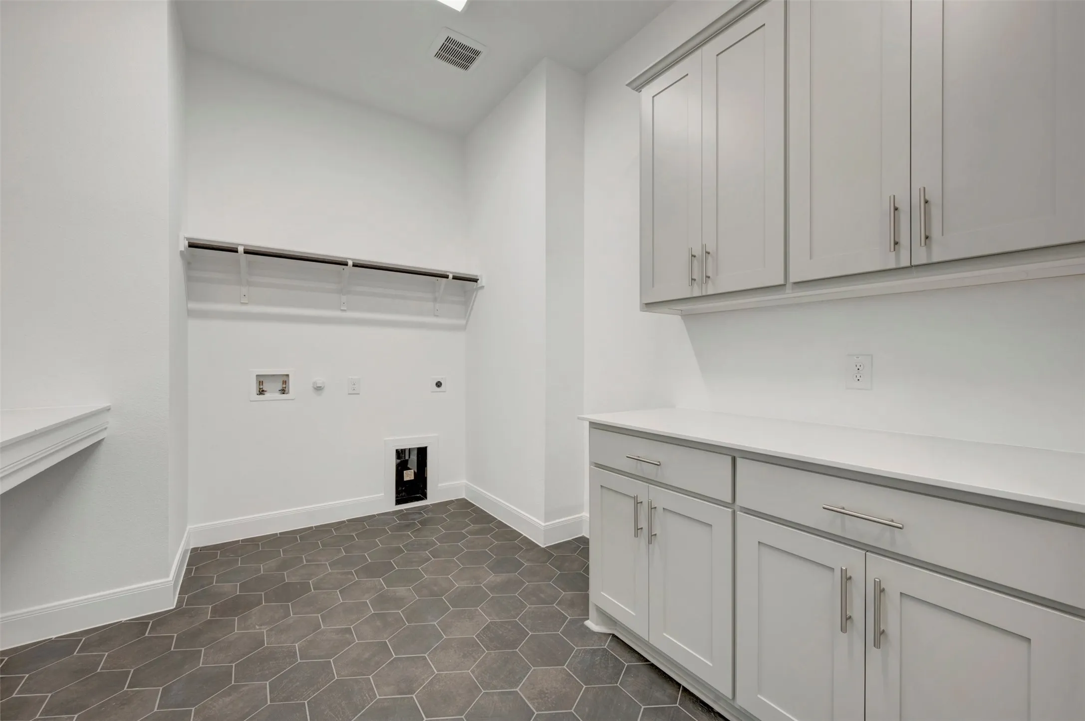 Hexagonal floor tiling, white walls, built-in shelving, white cabinetry, and white countertops