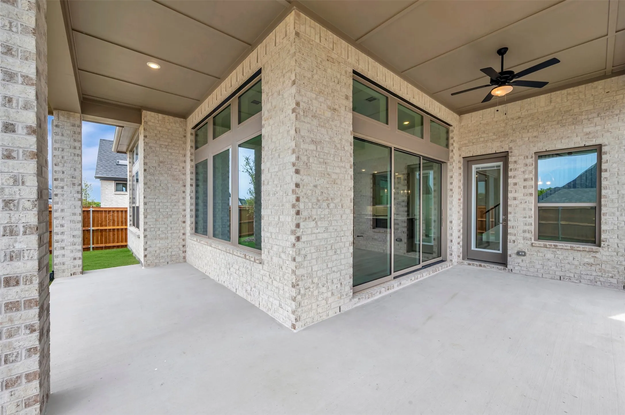 Covered patio featuring a concrete surface, a ceiling fan, and extensive brickwork