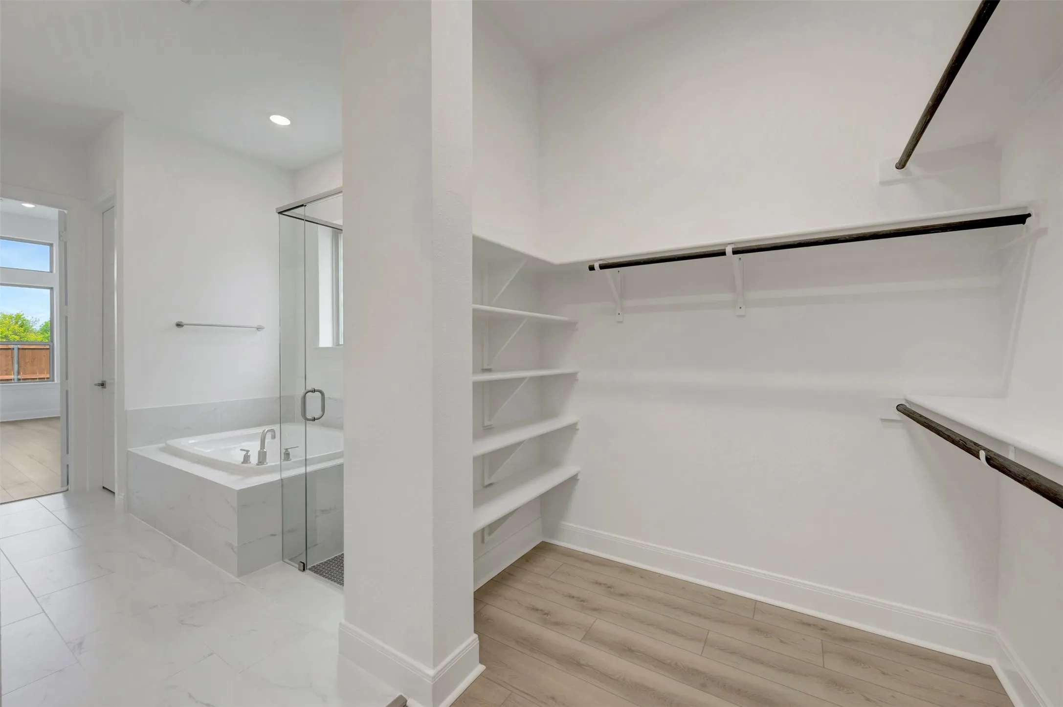 Soaking tub with tile surround, glass-enclosed shower, white tile flooring, and wood-finish flooring