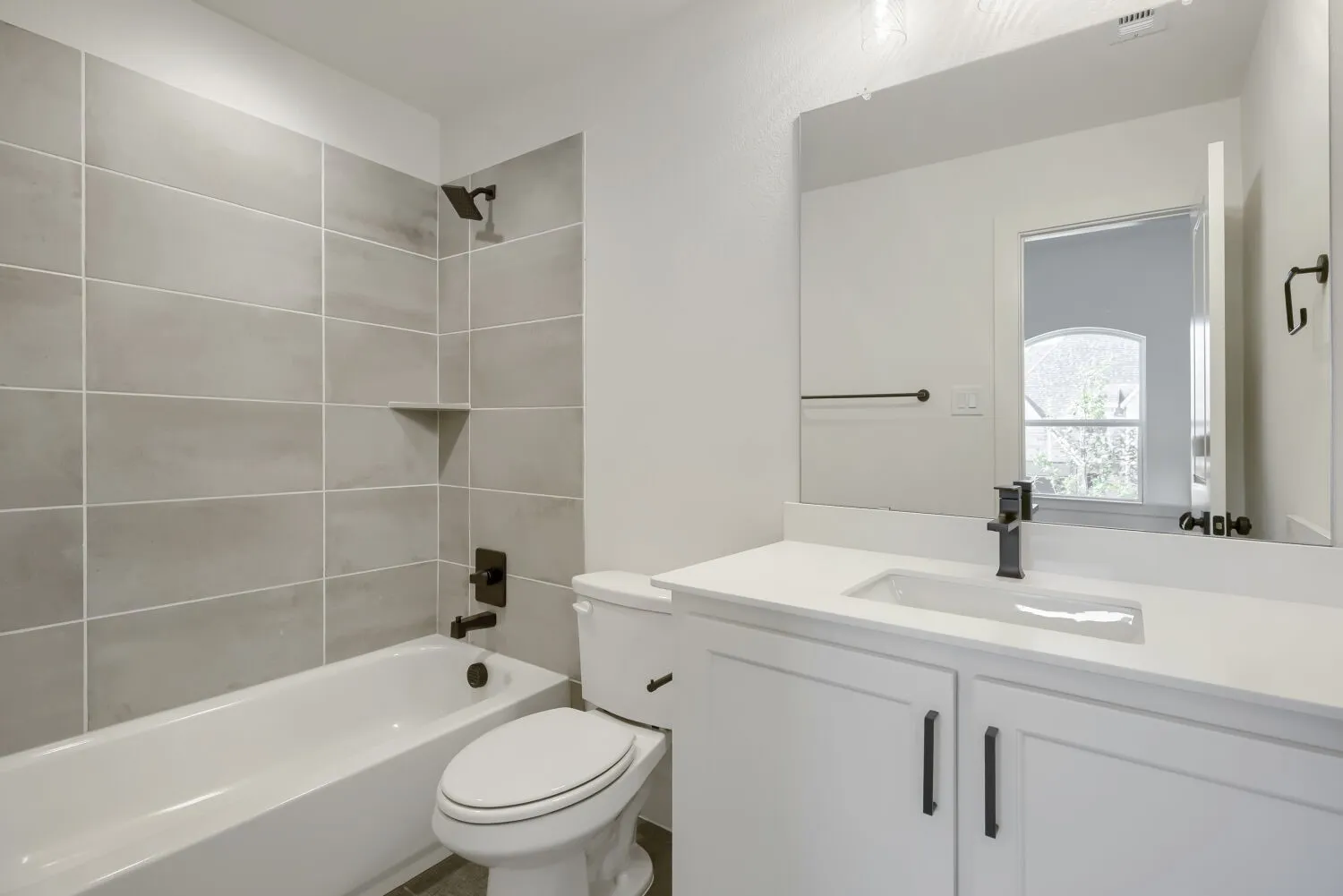 Bathroom featuring a white vanity with a rectangular sink, a large mirror, and dark bronze hardware