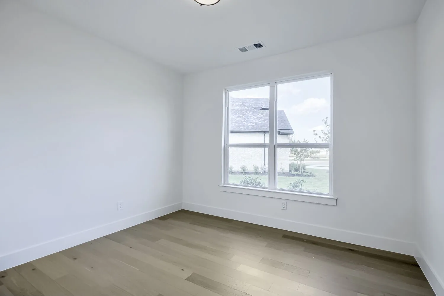 Bright interior space featuring wood-finish flooring and a large window with white trim