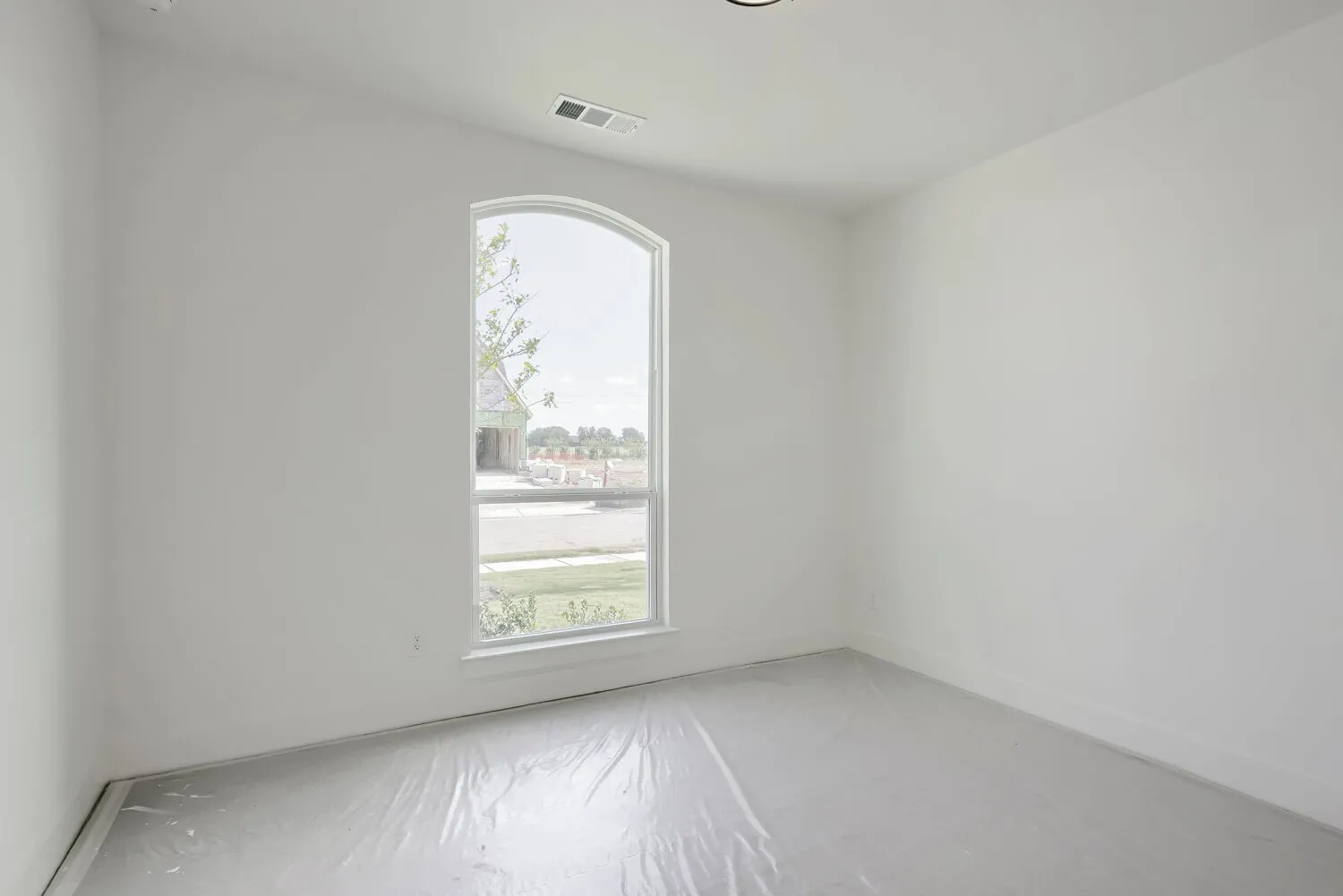 Room featuring an arched window, white walls, recessed ceiling lighting, and a floor vent