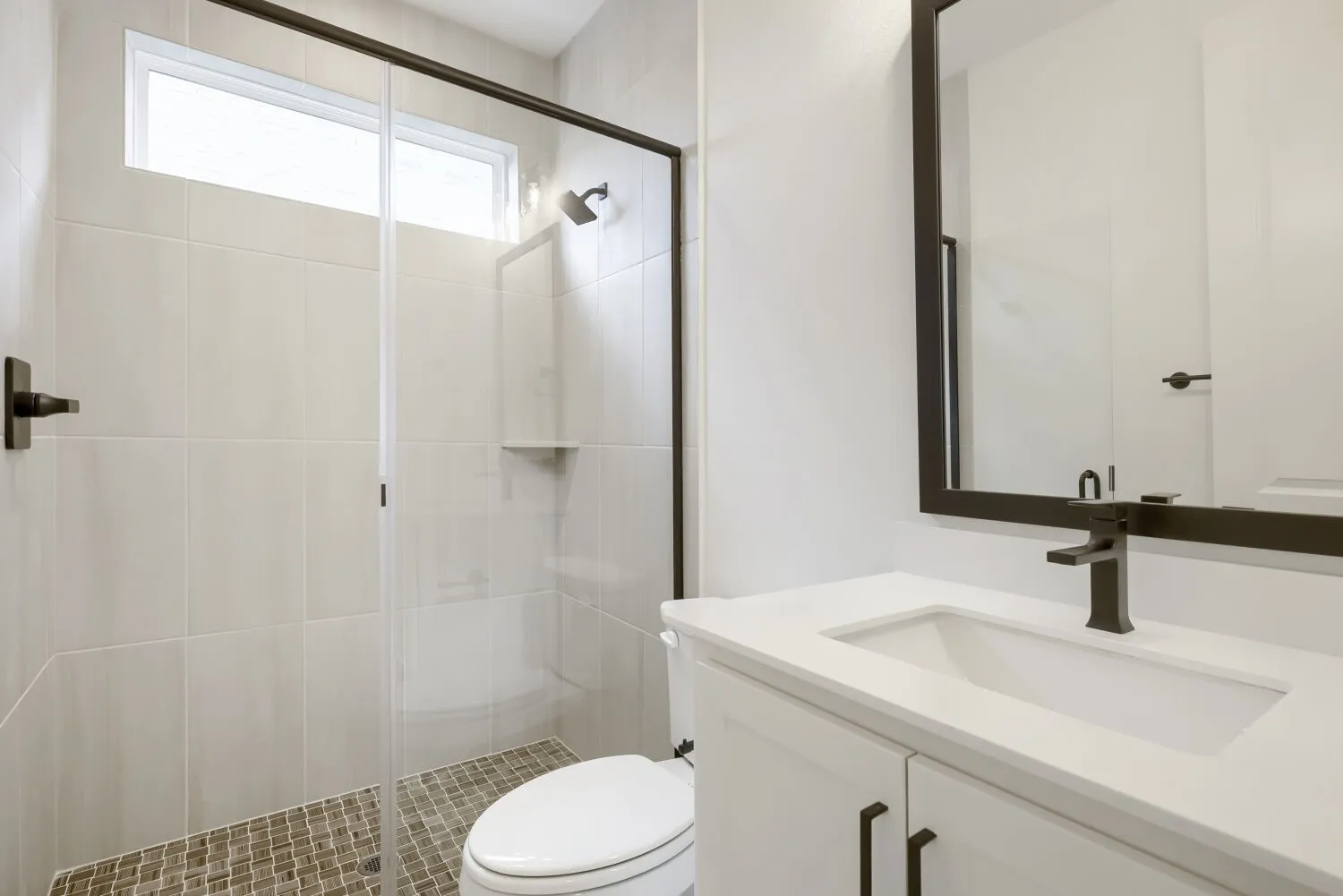 Bathroom featuring a walk-in shower with light-toned wall tiling and mosaic floor tiling