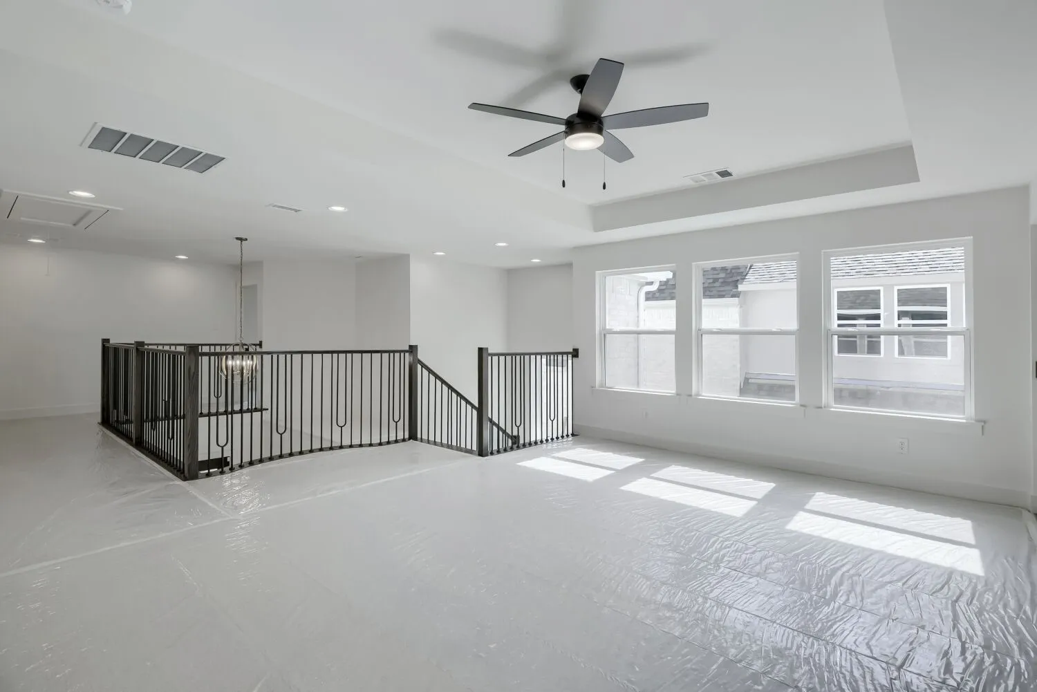 Spacious loft area featuring a black ceiling fan, recessed lighting, and a tray ceiling detail