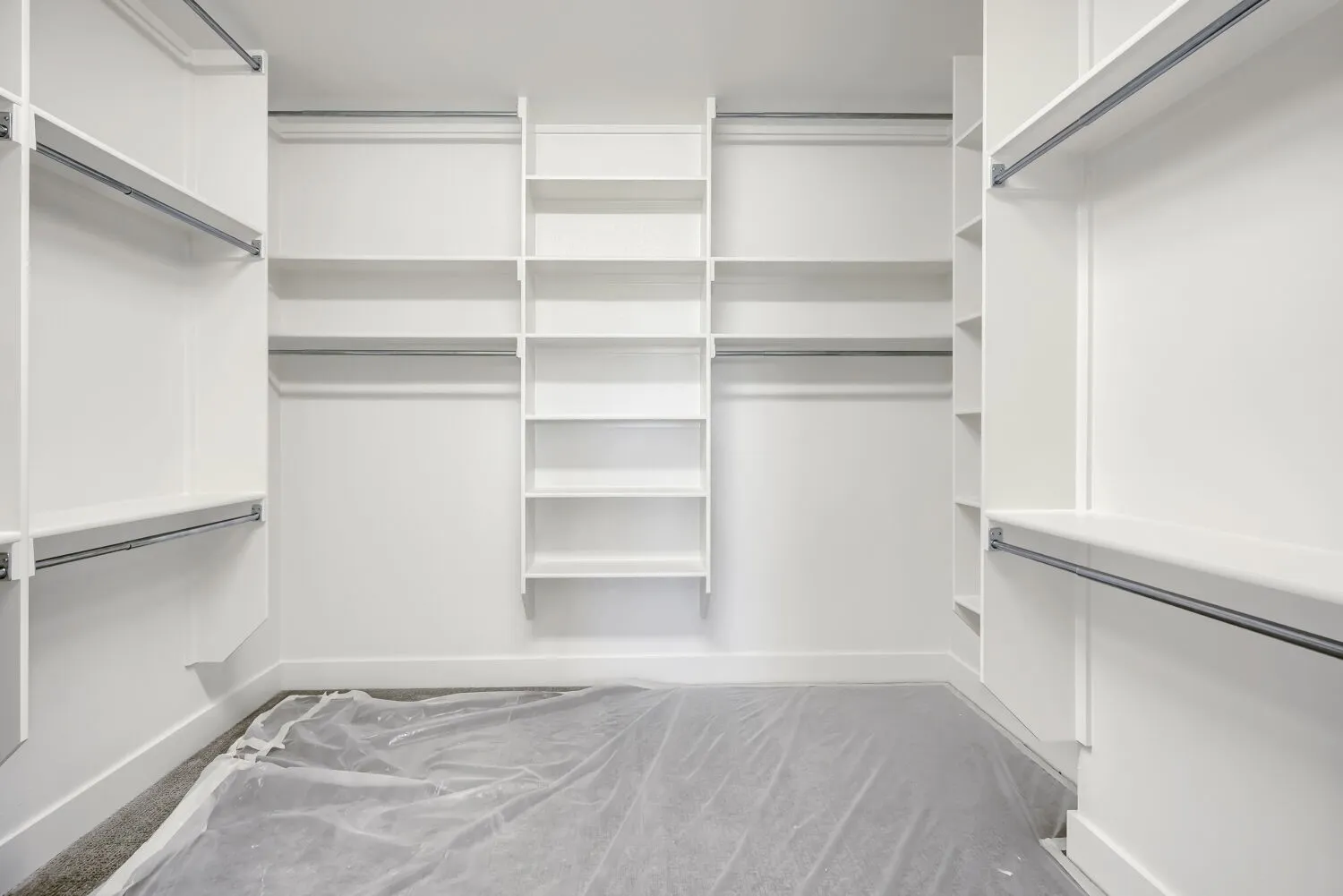Walk-in closet featuring extensive built-in shelving, multiple hanging rods, corner shelving units, and a bright white finish