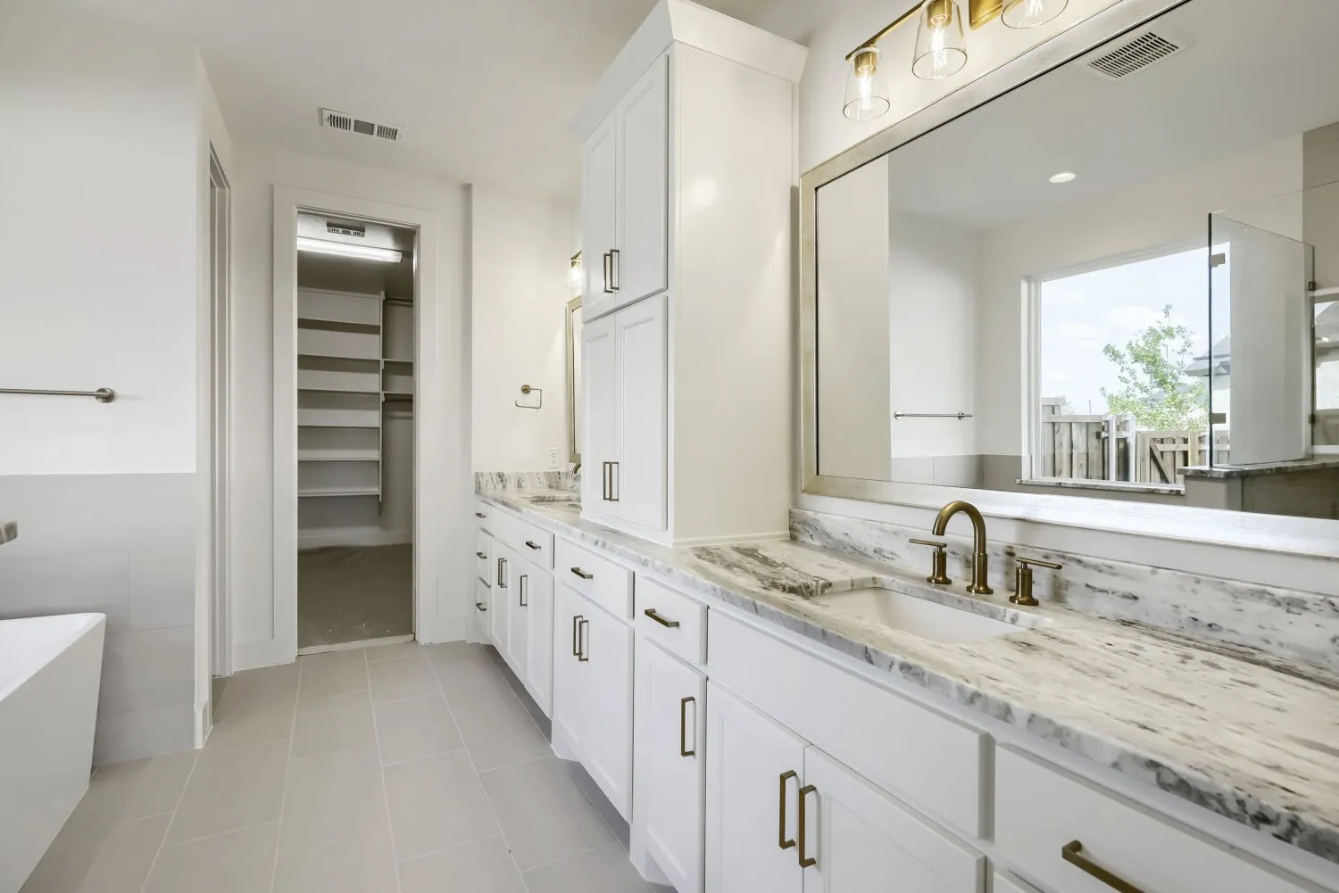 Spacious bathroom featuring a double vanity with white cabinetry and stone countertops
