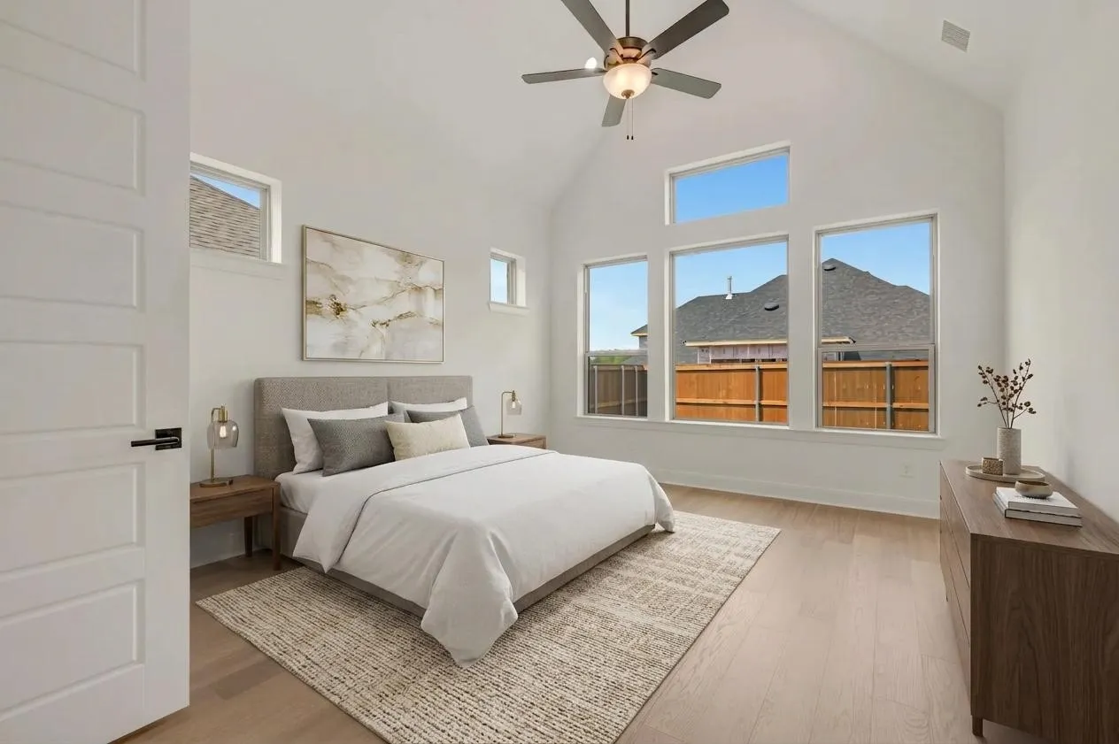 Vaulted ceiling with a ceiling fan, wood-finish flooring, and multiple windows
