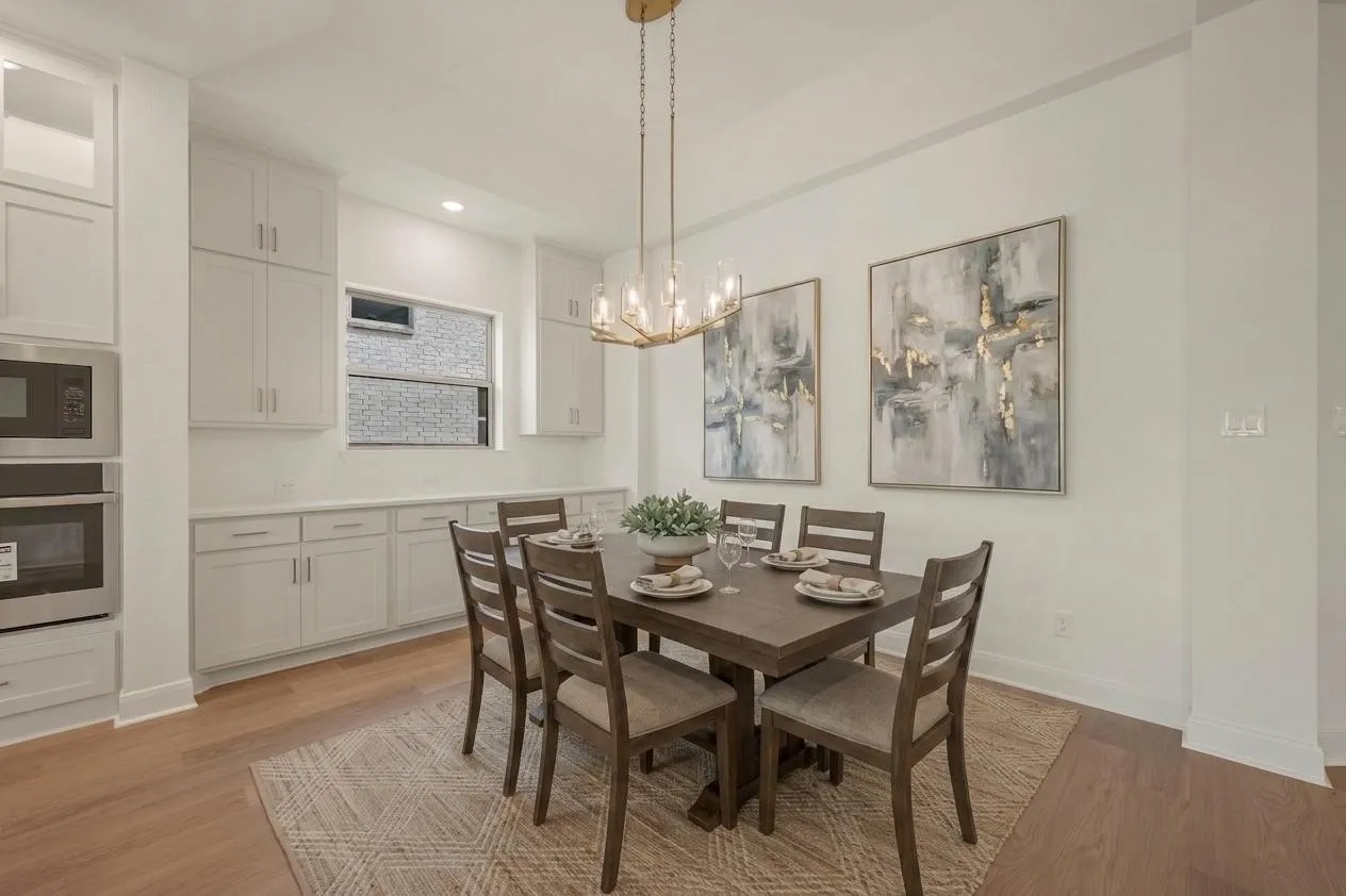 Integrated wall oven and microwave, extensive built-in cabinetry, wood-finish flooring, and a contemporary chandelier