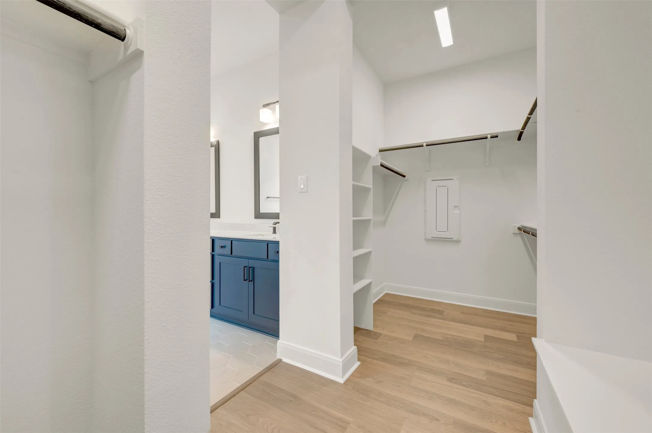 Walk-in closet with integrated shelving, multiple hanging rods, and wood-finish flooring