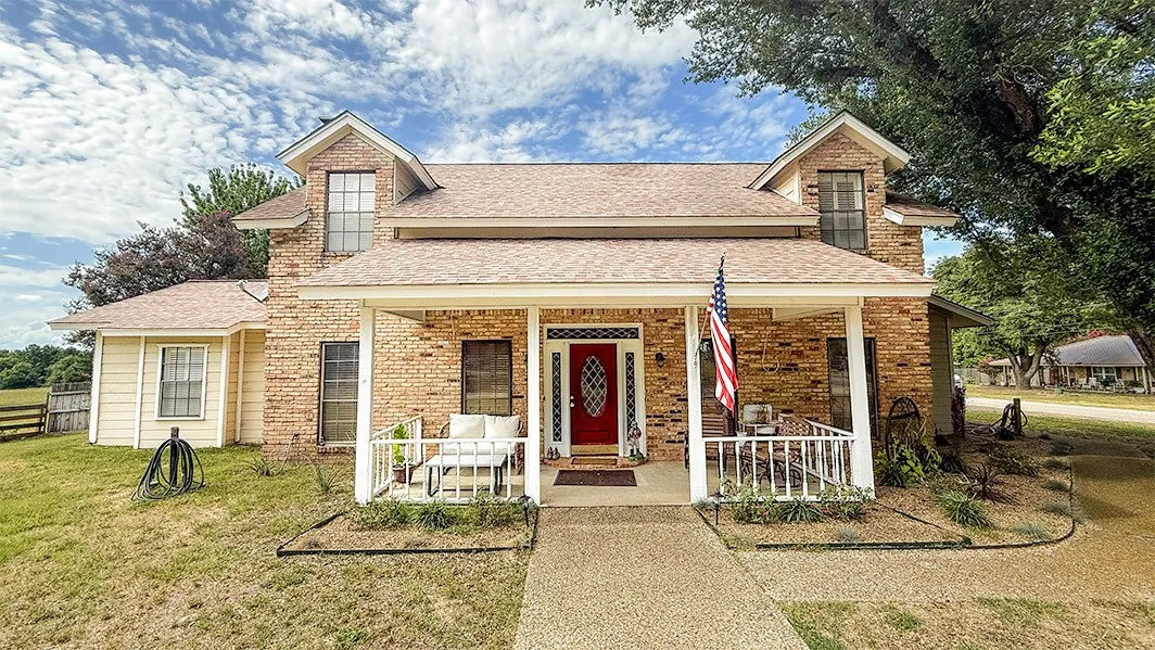 View of front of home featuring a front lawn, roof with shingles, brick siding, an outdoor living space, and covered porch