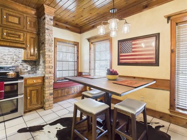 Dining area with light tile patterned floors, wood ceiling, and ornamental molding
