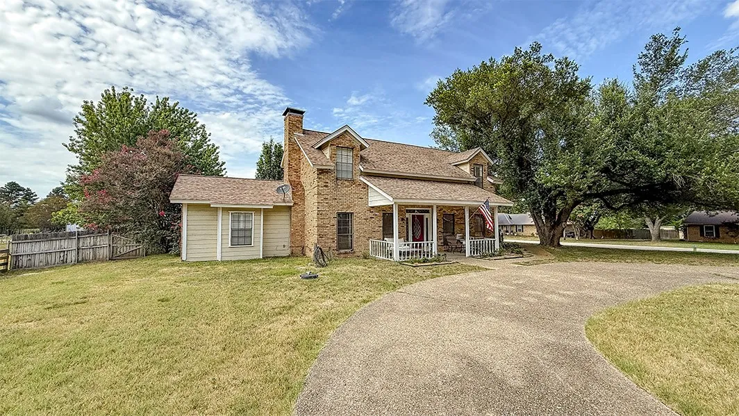 View of front of house with covered porch, a chimney, and driveway
