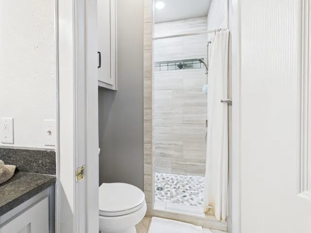 Bathroom featuring tiled shower and vanity