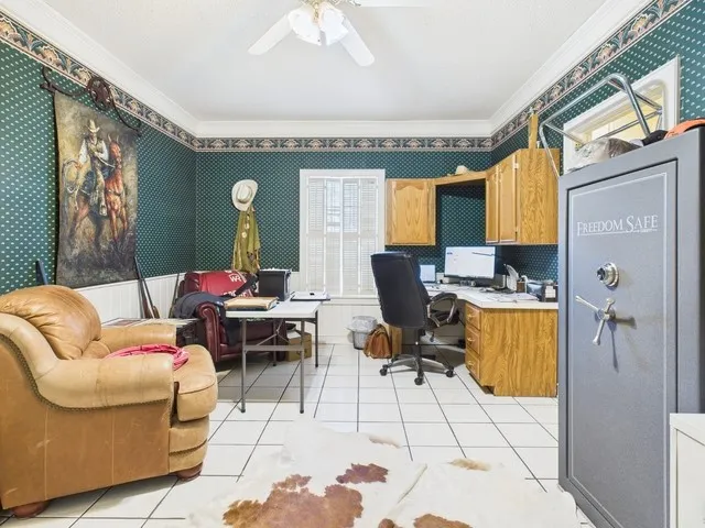 Home office with wallpapered walls, crown molding, light tile patterned floors, and ceiling fan