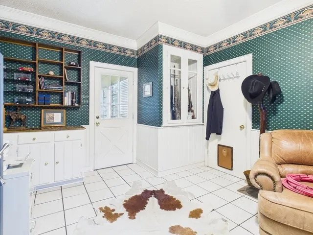 Entryway featuring ornamental molding, light tile patterned floors, and wallpapered walls