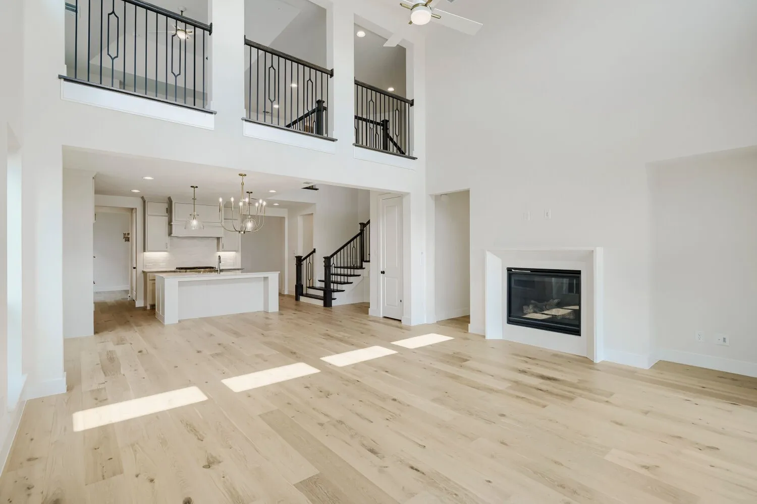 Expansive living area with high ceilings, wood-finish flooring, and a built-in fireplace
