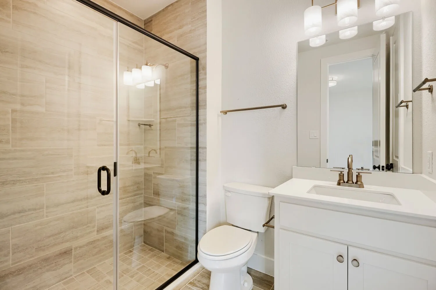 Modern bathroom featuring a glass-enclosed shower with tile surround and integrated bench