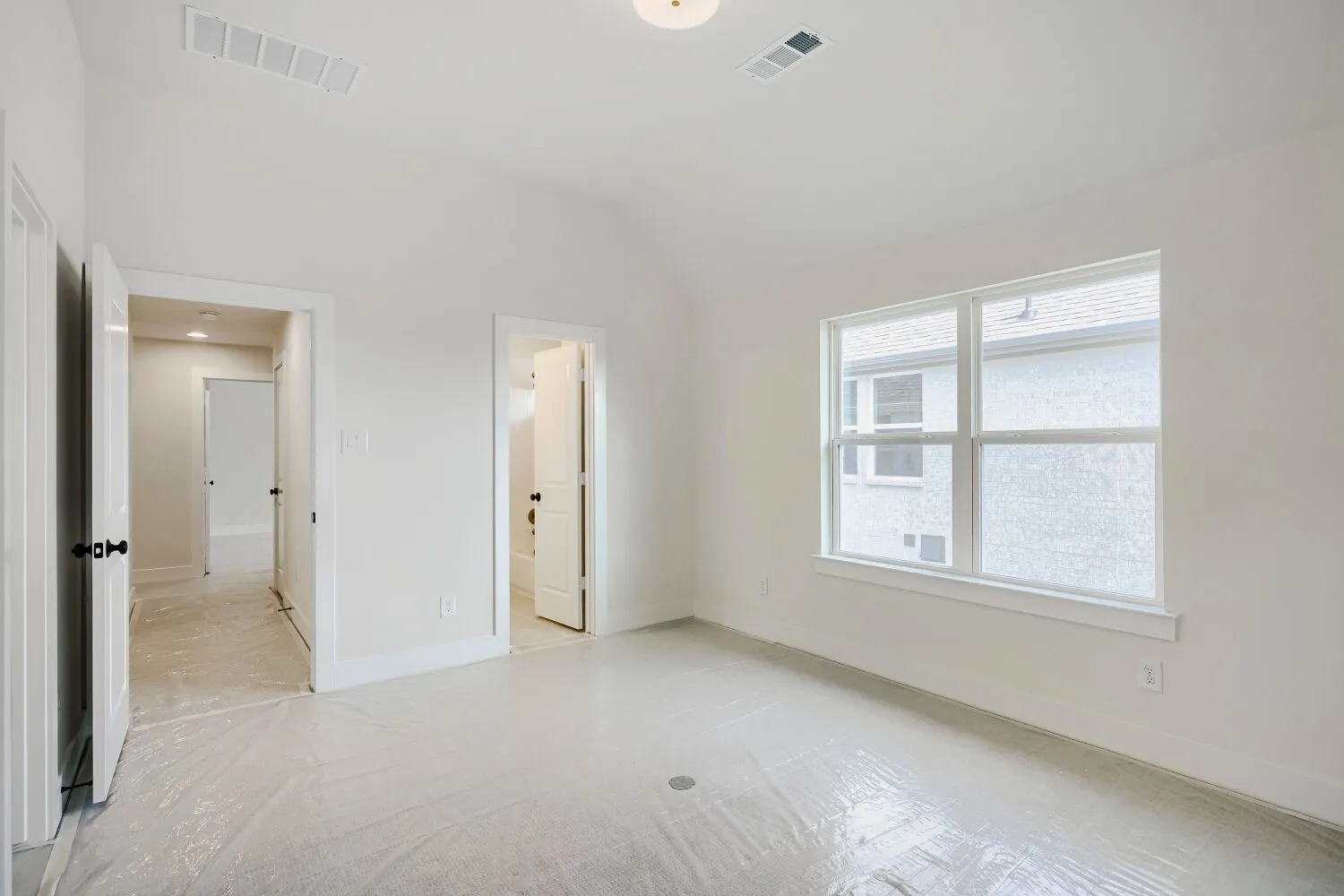 Bright interior space with a vaulted ceiling, white walls, and a large window providing ambient light