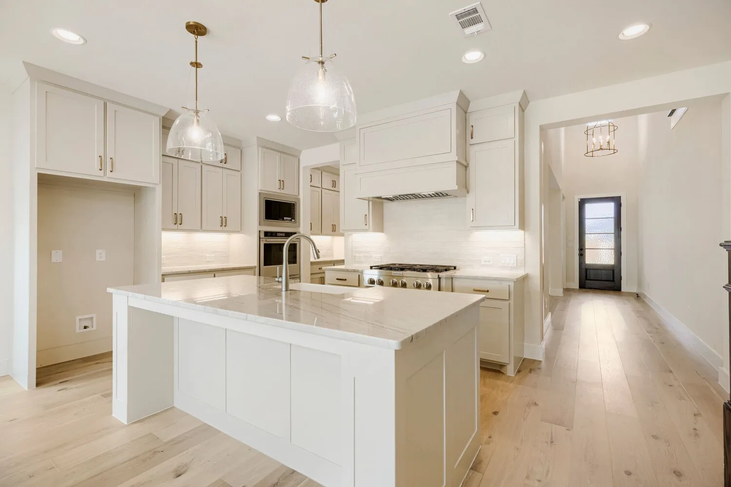 Bright kitchen featuring a substantial island with countertop, recessed lighting, double ovens, and a gas range