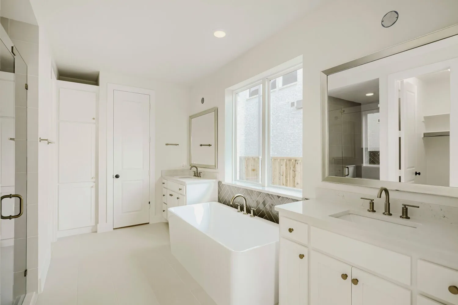 Contemporary bathroom featuring a freestanding soaking tub, dual vanity with undermount sinks, and a glass-enclosed shower