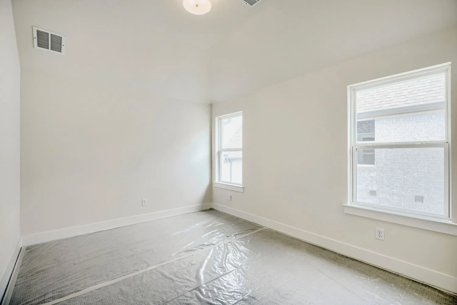Bright, neutral-toned room featuring a vaulted ceiling and two windows with white blinds