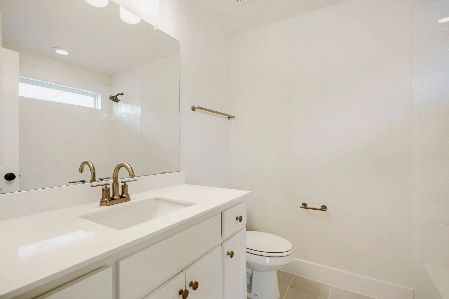 Bathroom vanity featuring a single basin, a white countertop, and brass-finish fixtures
