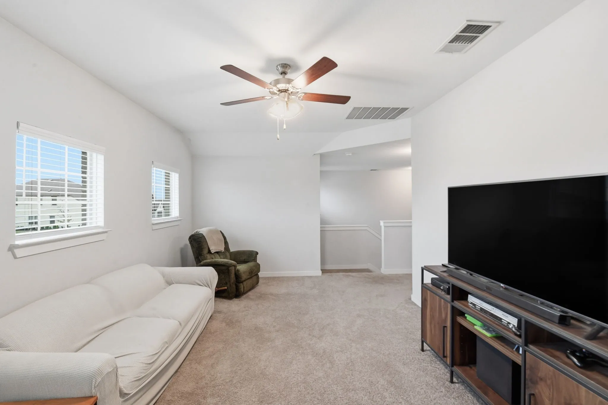 Sitting room with an upstairs landing, light carpet, ceiling fan, and lofted ceiling