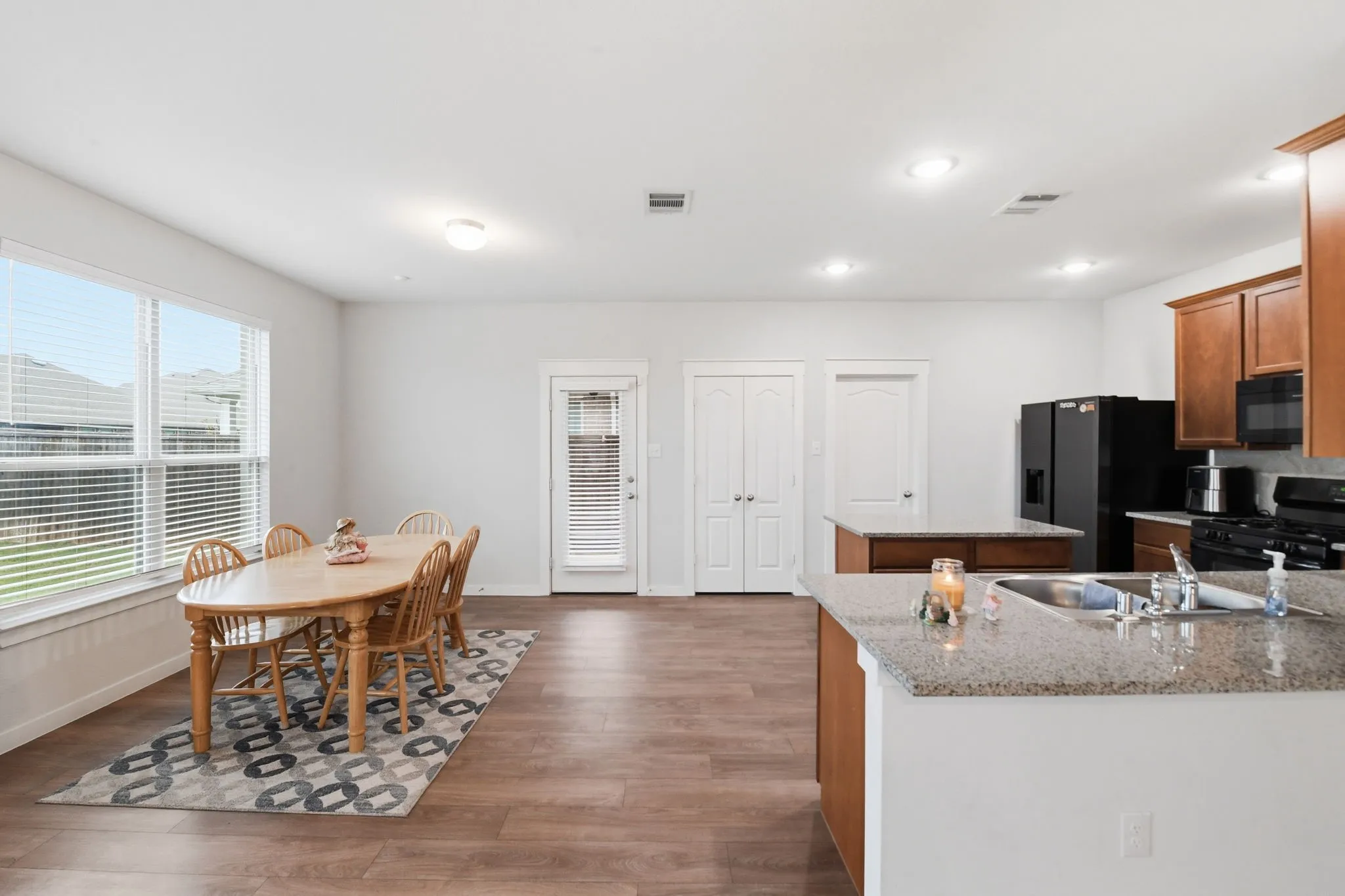 Kitchen featuring black appliances, dark wood finished floors, wood finish cabinetry, a center island, and a peninsula
