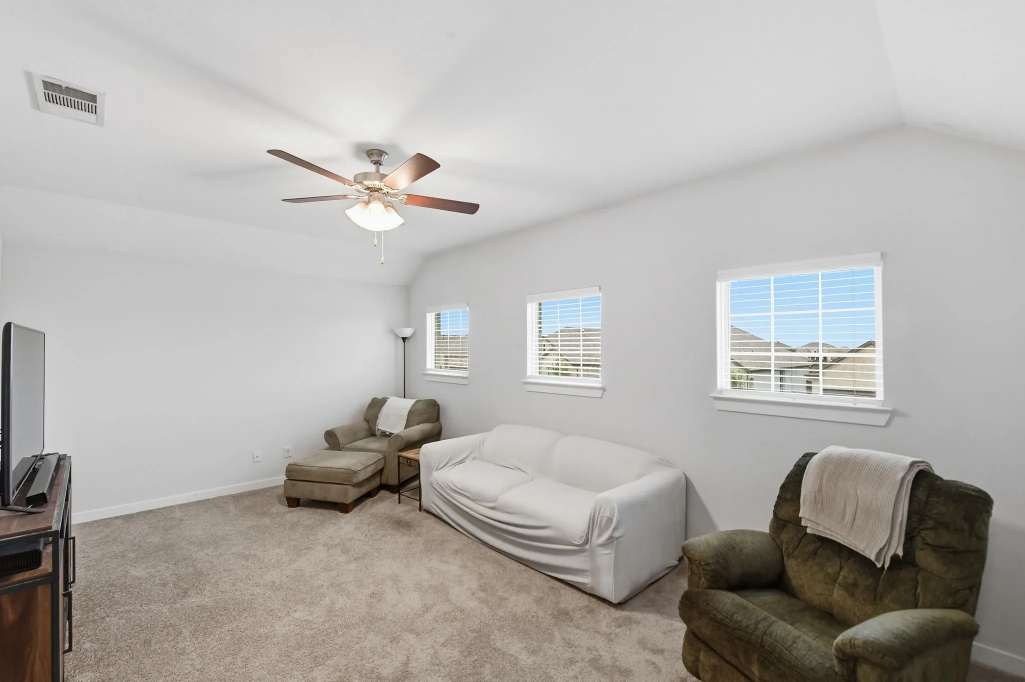 Living area with vaulted ceiling, carpet, and ceiling fan