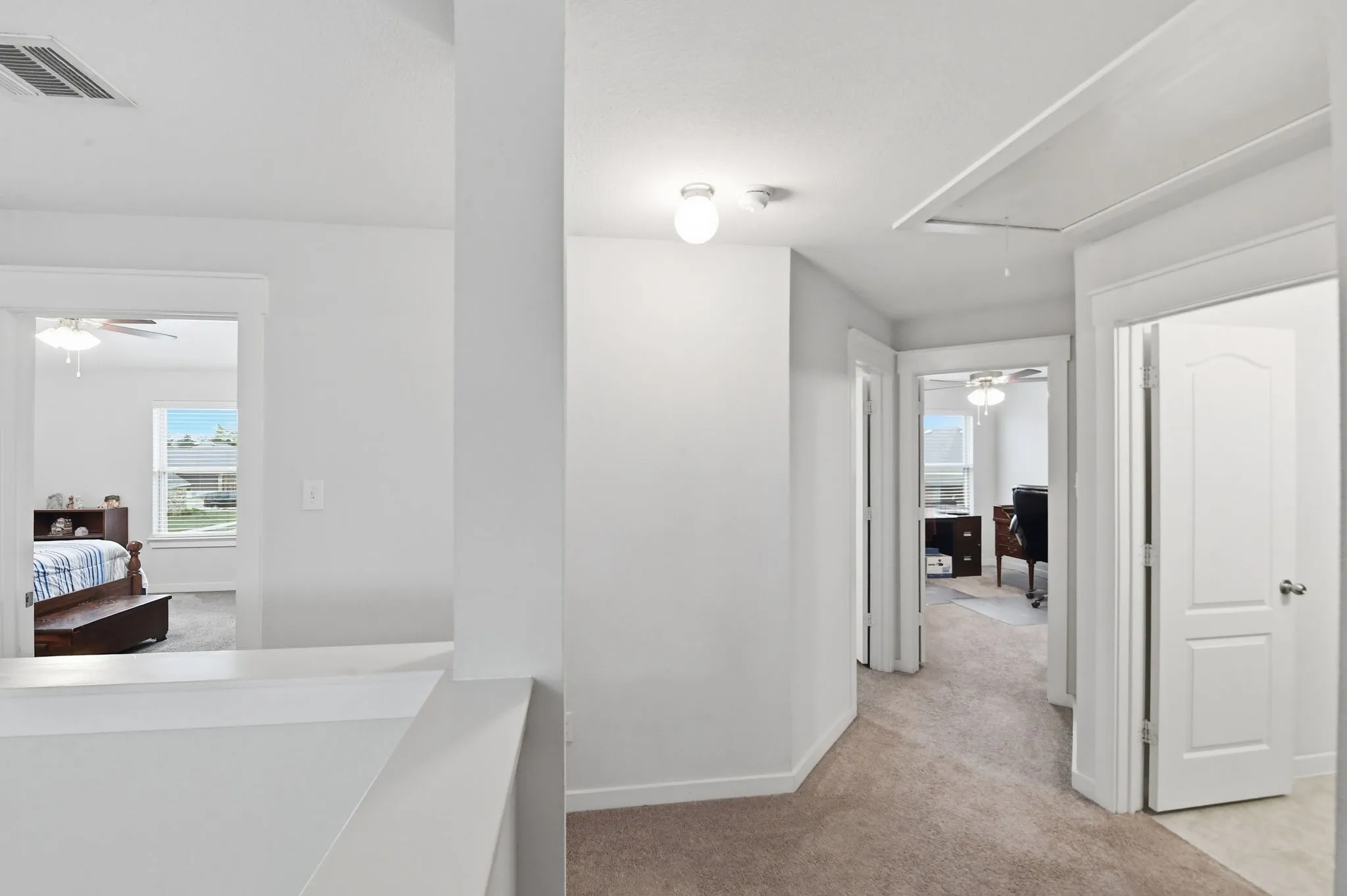Hallway featuring attic access and light carpet
