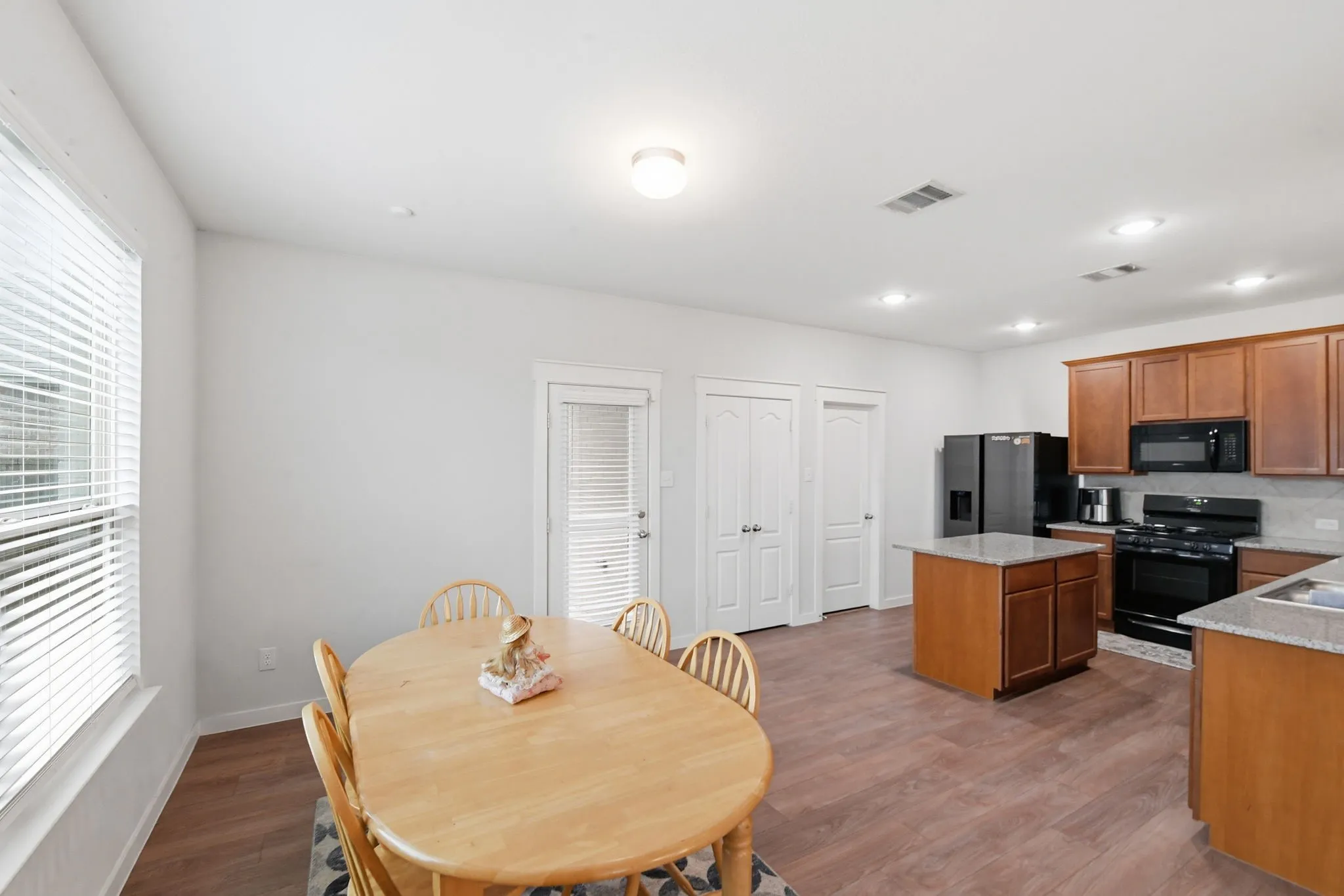 Kitchen featuring black appliances, dark wood-style floors, a center island, and wood finish cabinets