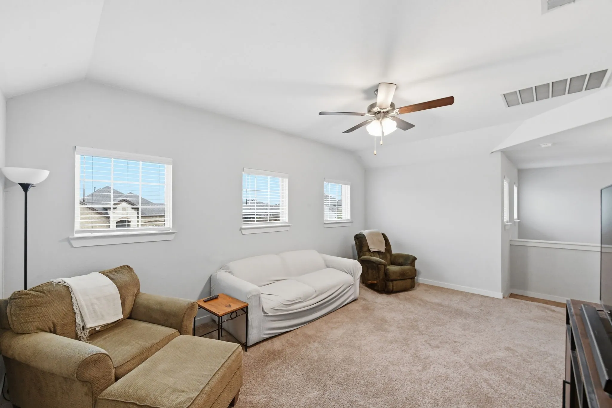 Living area with lofted ceiling, carpet flooring, and a ceiling fan
