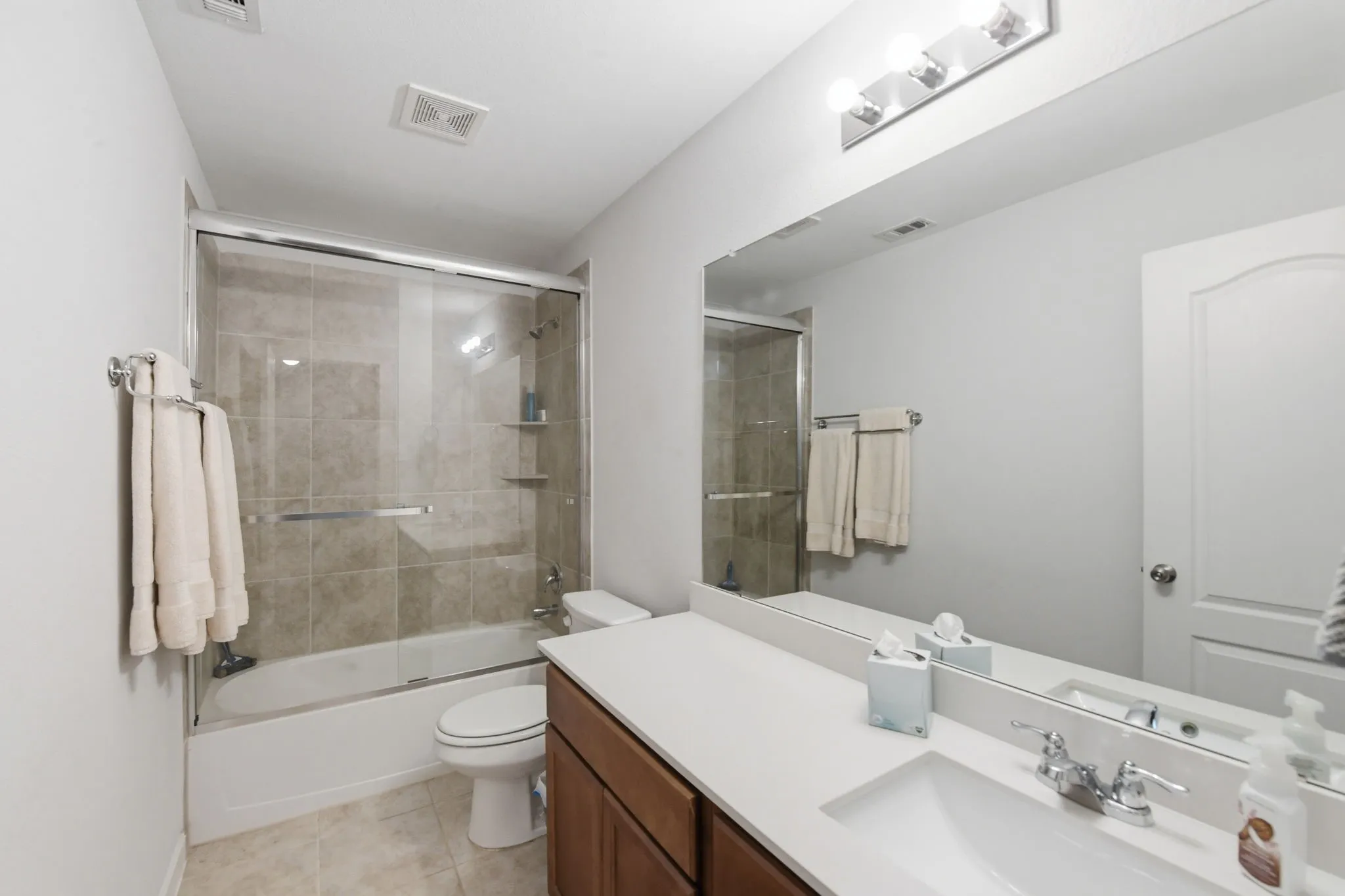 Full bath with vanity, enclosed tub / shower combo, and light tile patterned floors
