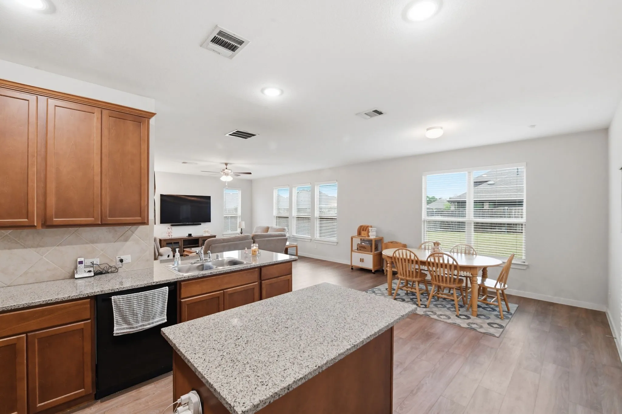 Kitchen featuring light stone counters, dishwasher, open floor plan, and a kitchen island