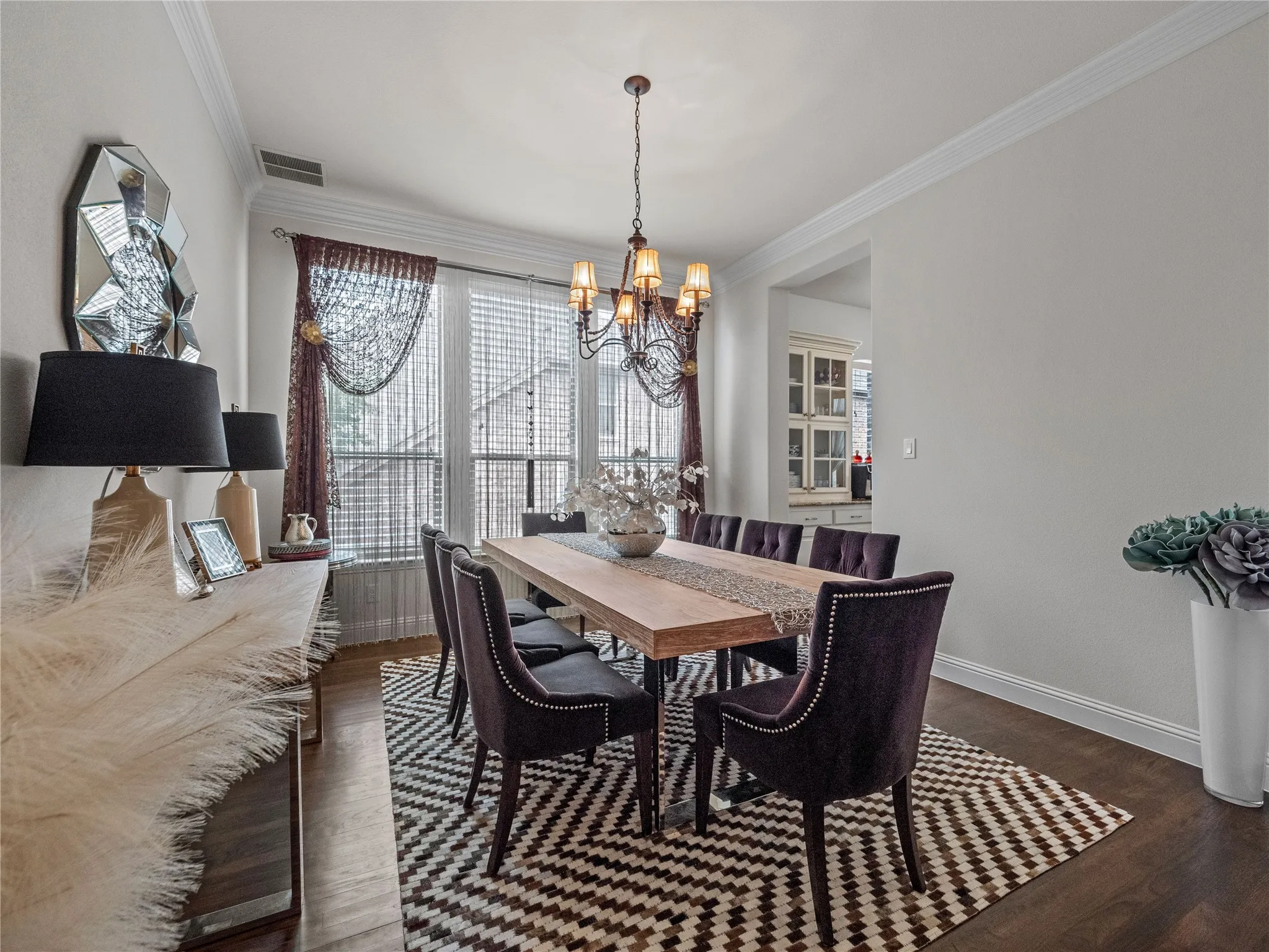 Dining space with ornamental molding, healthy amount of natural light, dark wood-style flooring, and suspended lighting
