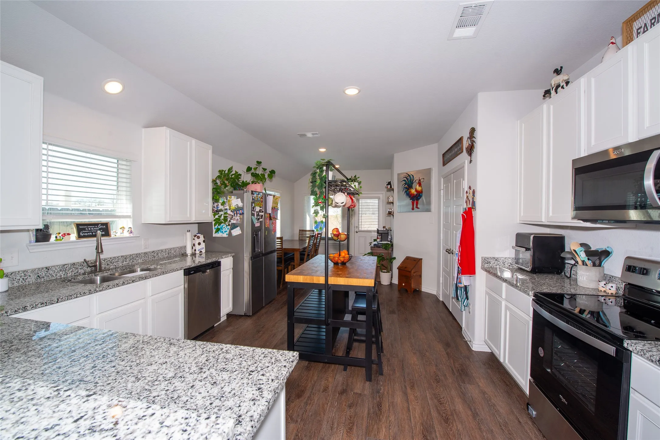 Kitchen with stainless steel appliances, light stone countertops, healthy amount of natural light, white cabinets, and recessed lighting