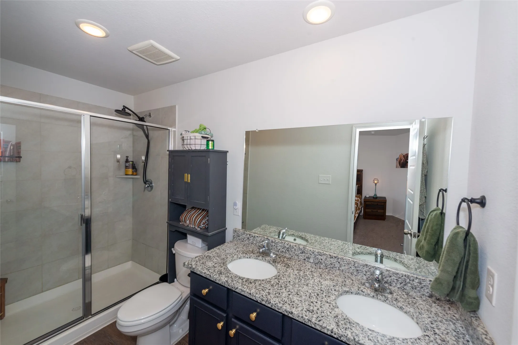 Full bathroom featuring double vanity, a shower stall, ensuite bathroom, and recessed lighting