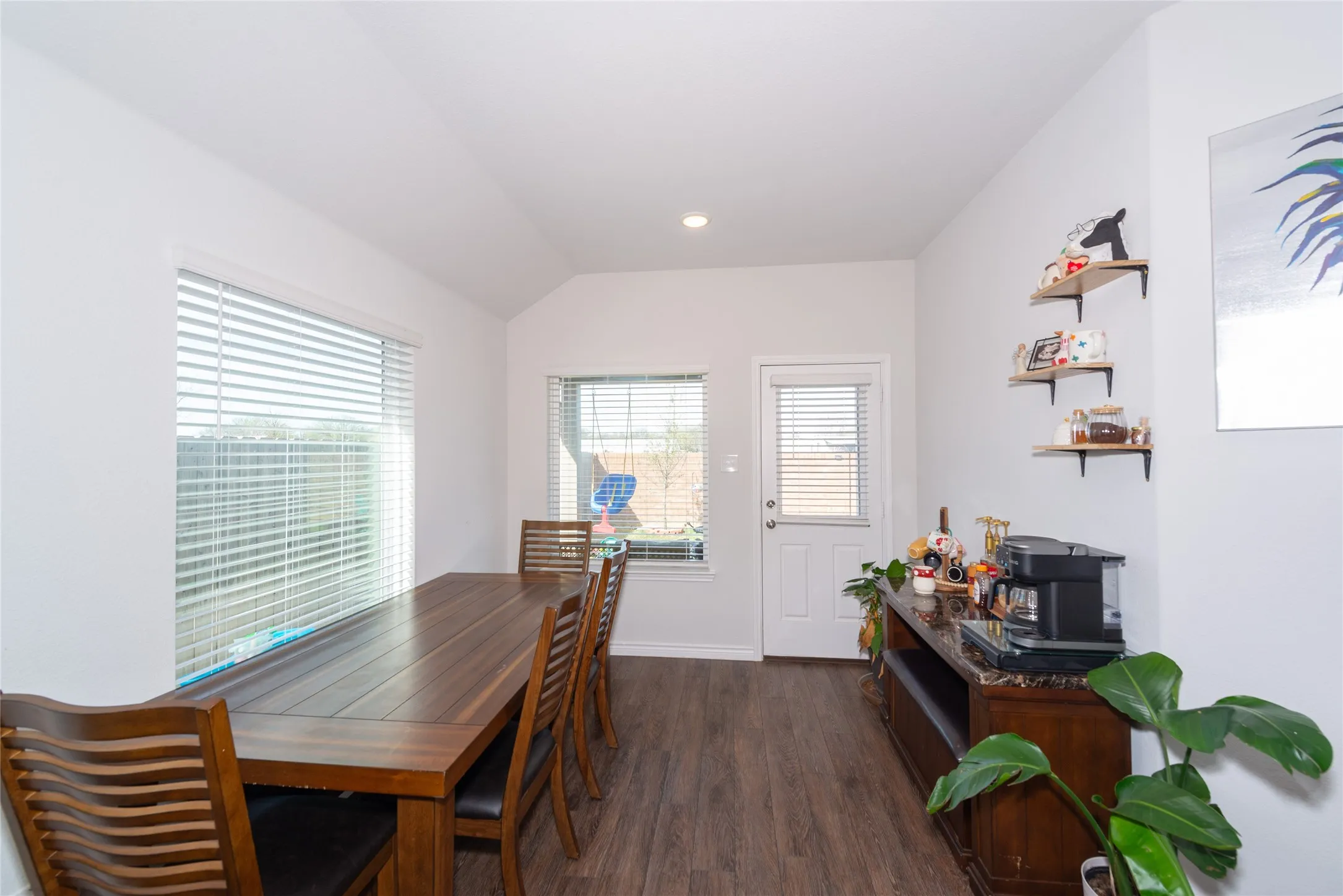 Dining space featuring dark wood-style flooring, lofted ceiling, and recessed lighting