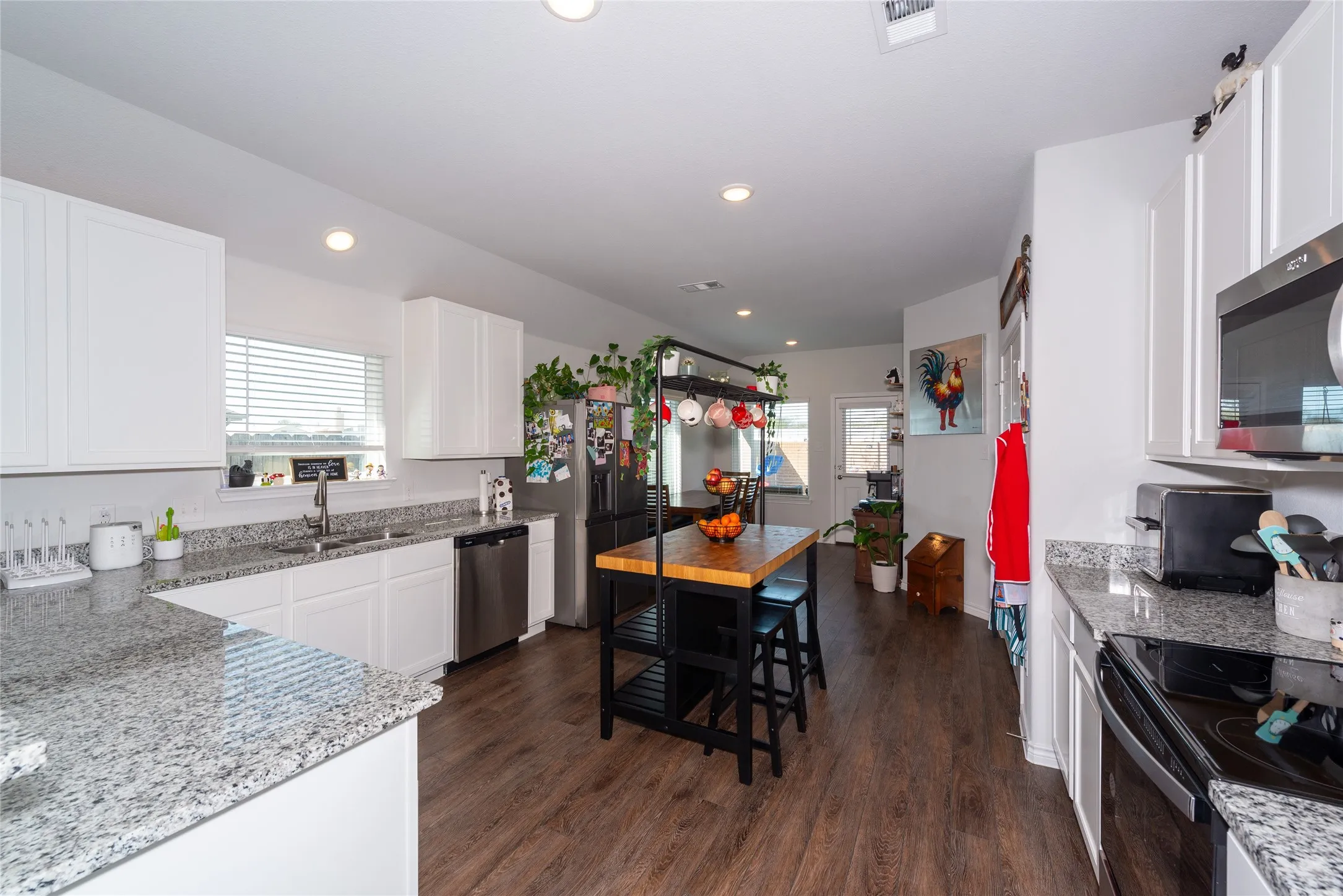 Kitchen featuring light stone counters, white cabinetry, dark wood finished floors, stainless steel appliances, and recessed lighting