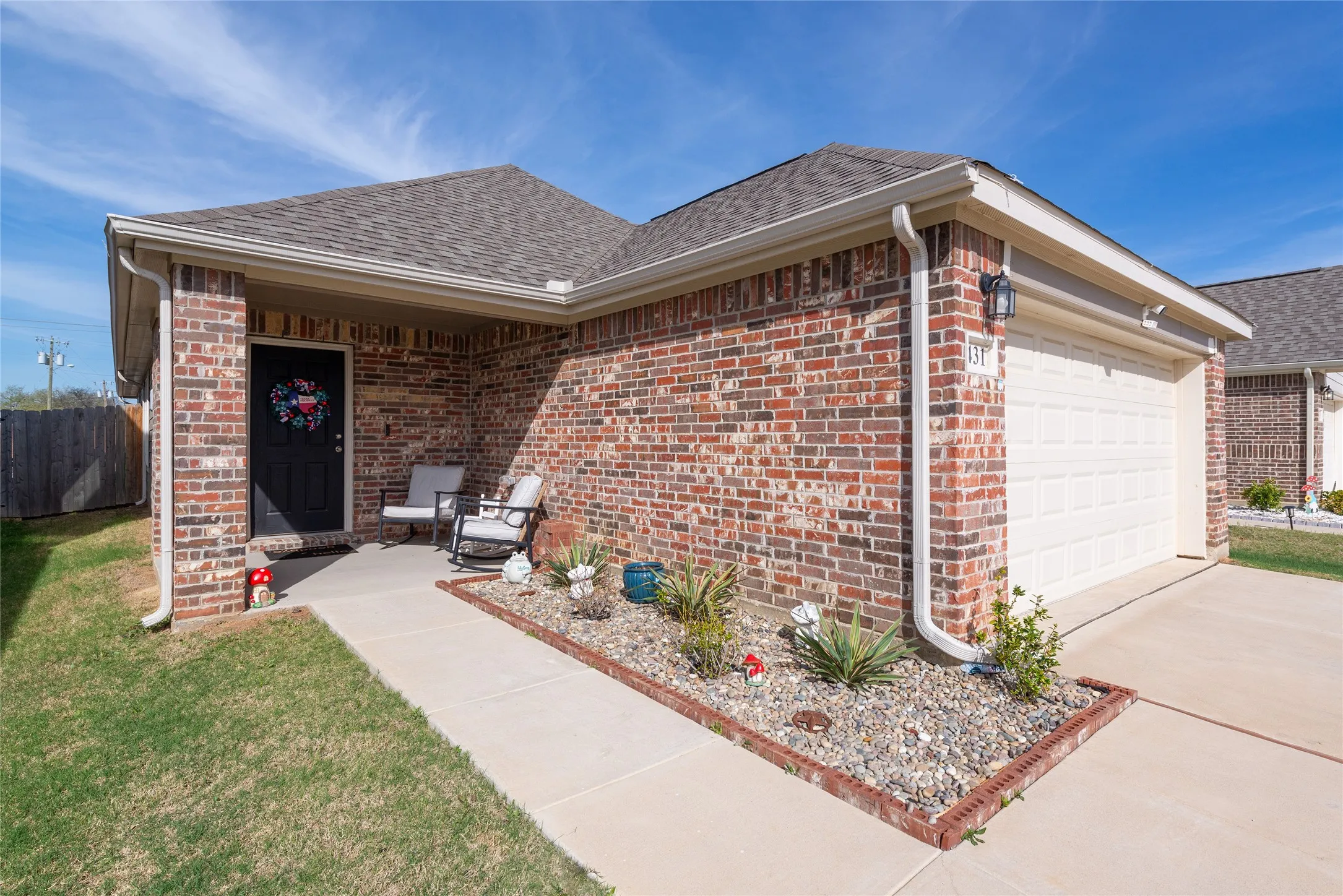 View of front of property with a garage, brick siding, driveway, and roof with shingles