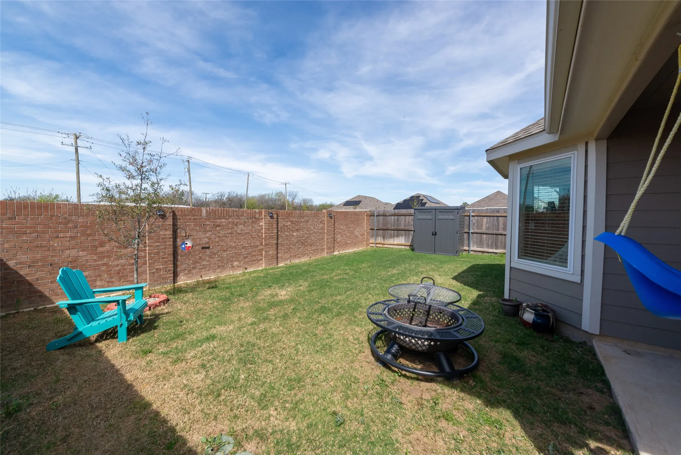 Fenced backyard featuring a fire pit and a storage unit