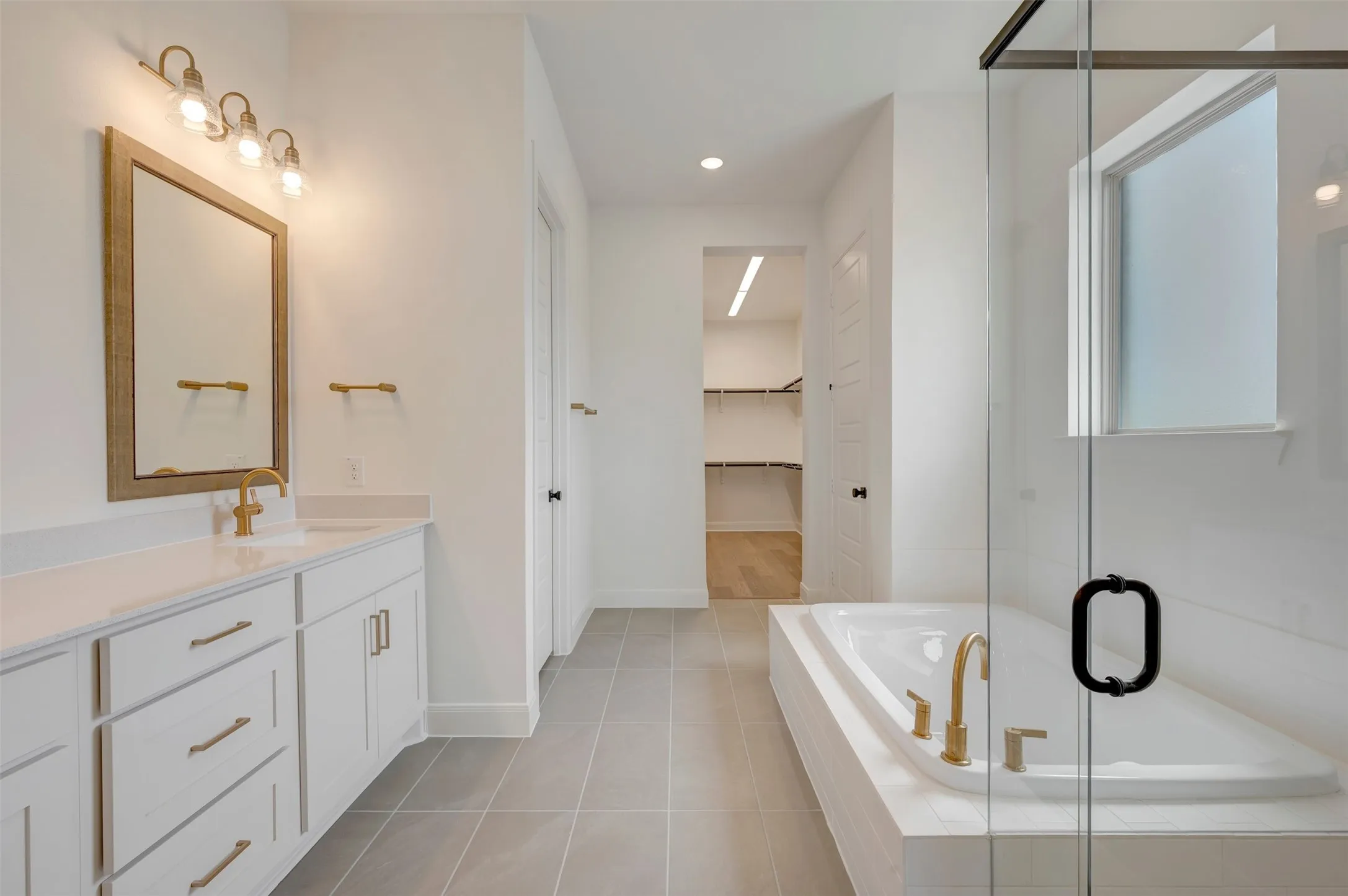 Dual vanity with white cabinetry, gold-finish fixtures, and light countertops