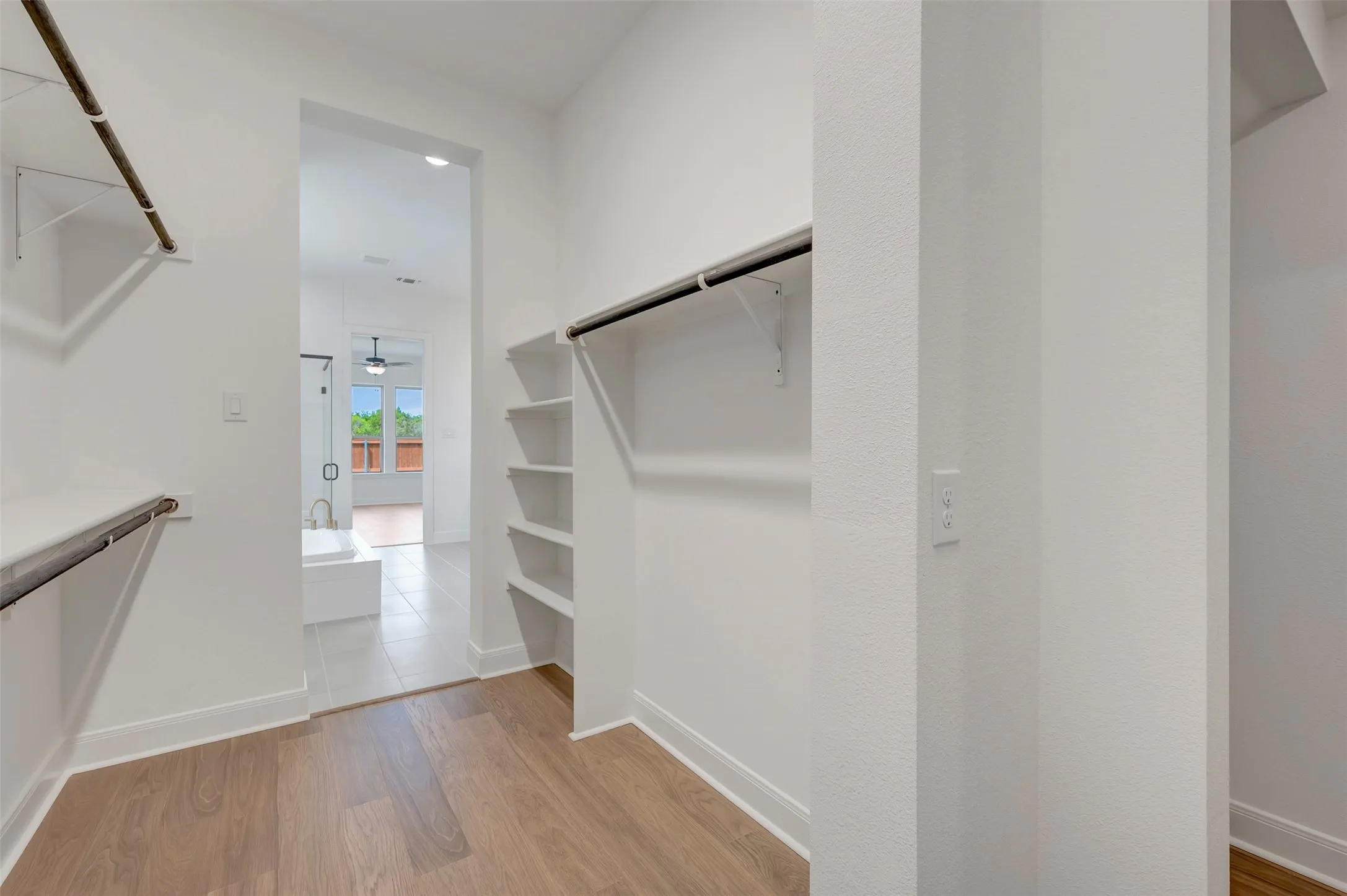 Walk-in closet featuring wood-finish flooring, built-in shelving, and metal hanging rods